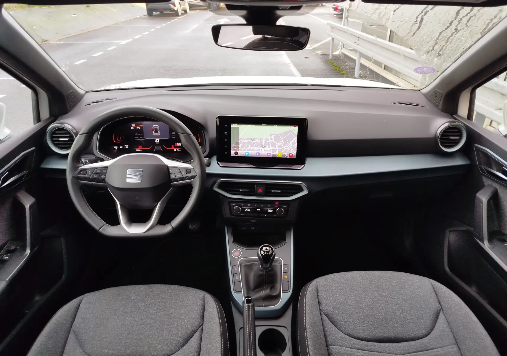 Vue intérieure frontale du tableau de bord et volant du SEAT Arona 2023, avec écran tactile et levier de vitesse manuel.