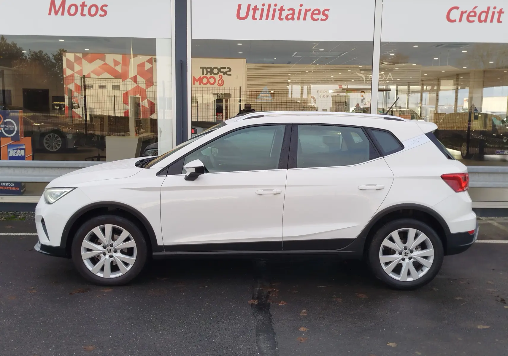 Vue de profil côté gauche d'un SEAT Arona blanc Candy 2023, avec jantes alliage et détails noirs contrastants.