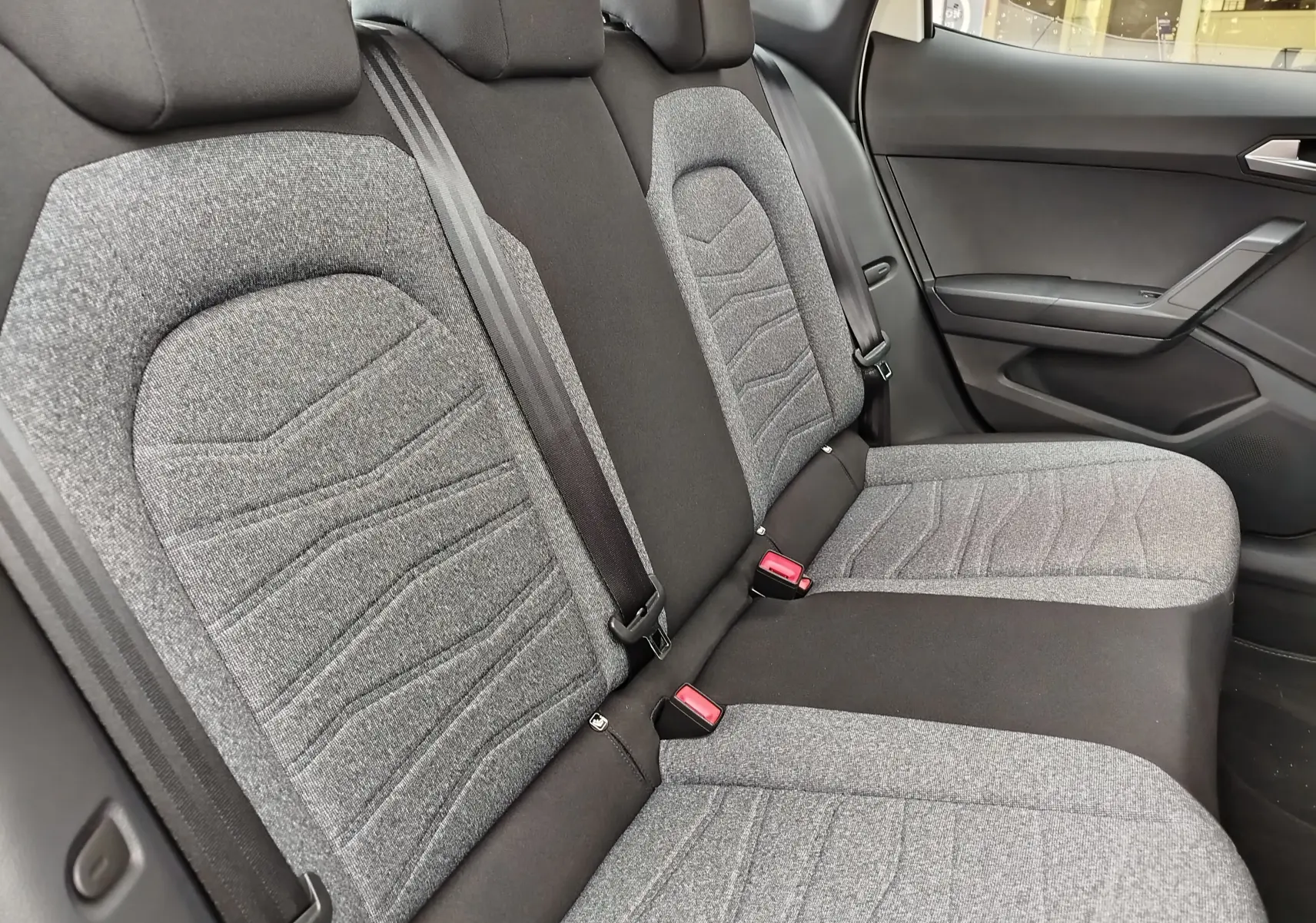 Vue latérale droite des sièges arrière gris tissu avec ceintures noires dans le SEAT Arona 2023 blanc Candy.