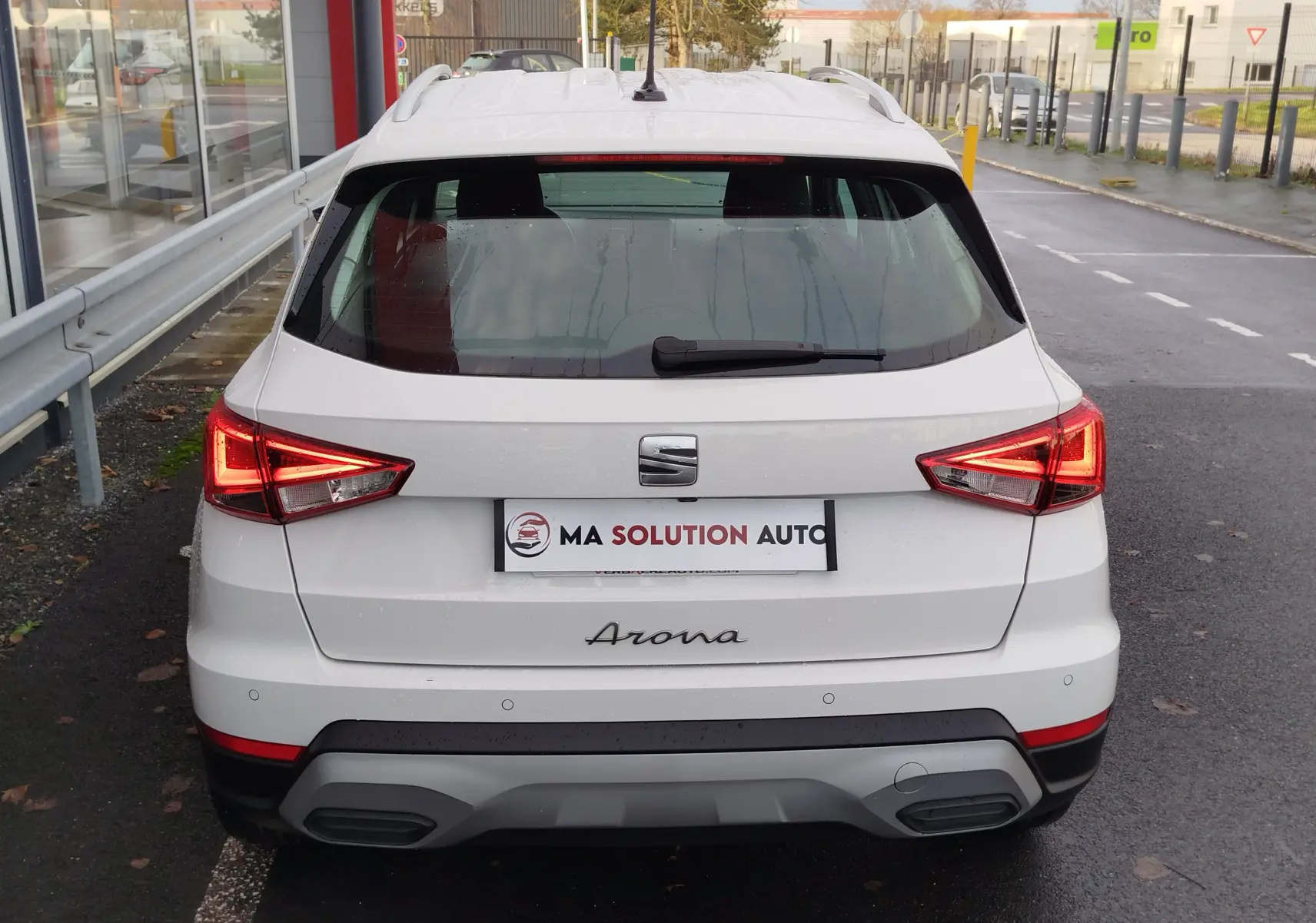 Vue arrière d'un SEAT Arona blanc Candy 2023 avec feux allumés et détails noirs sur le pare-chocs.