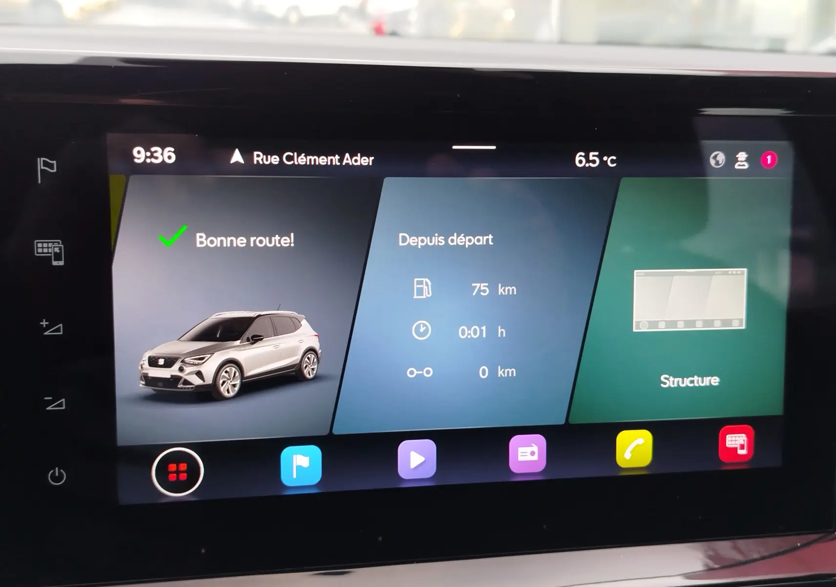 Écran tactile affichant une SEAT Arona blanc candy en 3/4 avant avec informations de trajet et météo à 6,5°C.