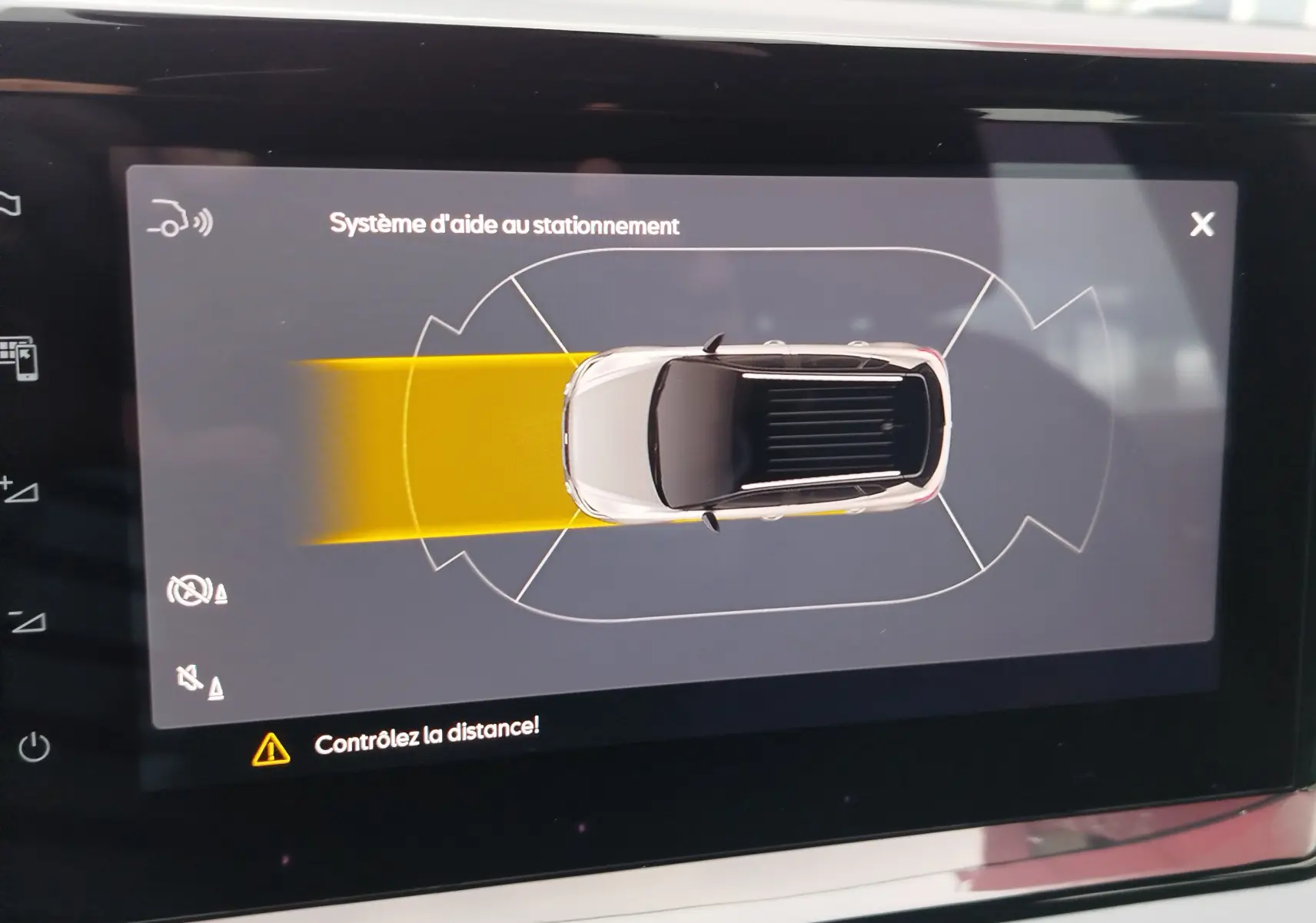 Affichage du système d'aide au stationnement avec vue aérienne du SEAT Arona blanc candy, signalant un obstacle à l'arrière.