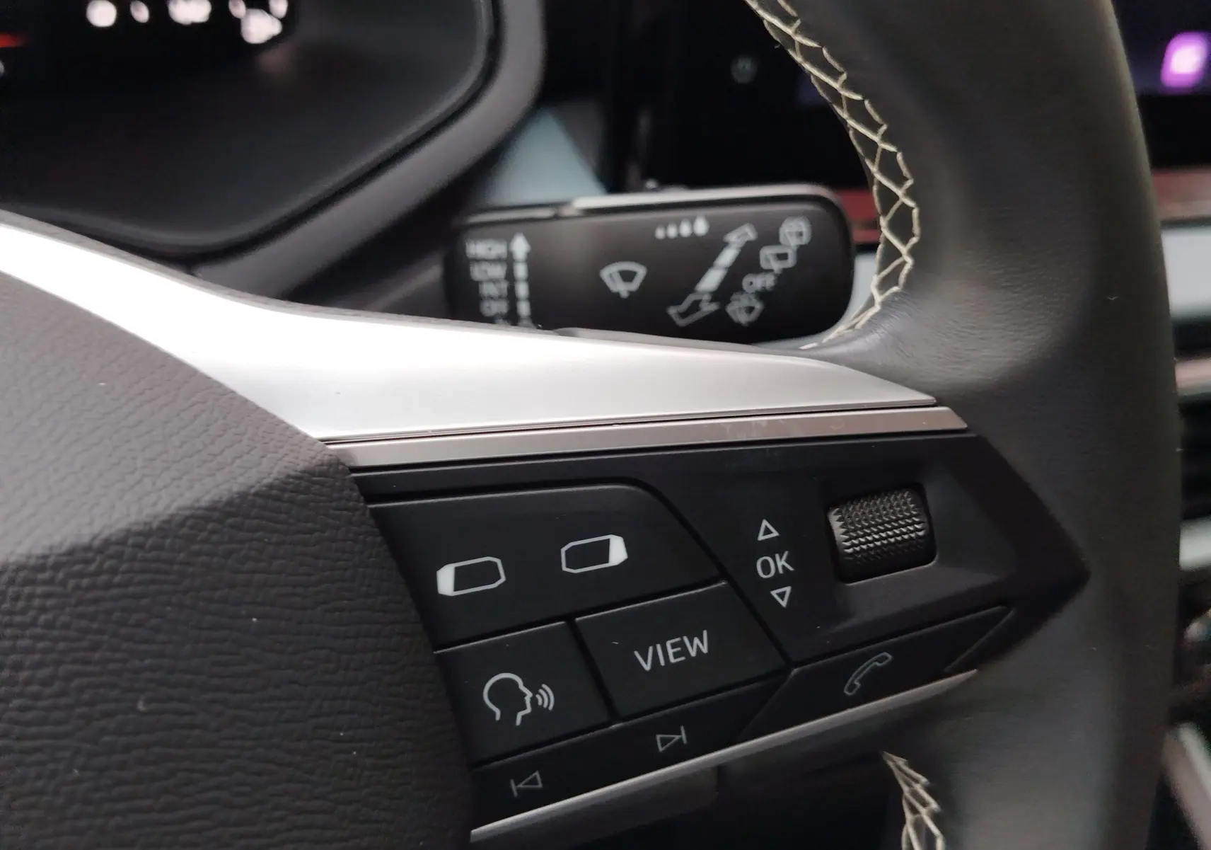 Gros plan sur les commandes au volant côté gauche du SEAT Arona 2023, cuir noir avec surpiqûres blanches.