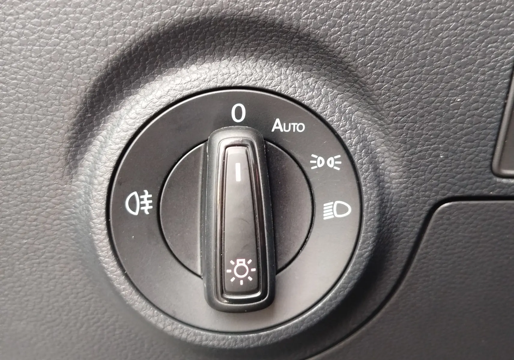 Gros plan sur la molette de réglage des phares du tableau de bord du SEAT Arona blanc, avec options d’éclairage visibles.