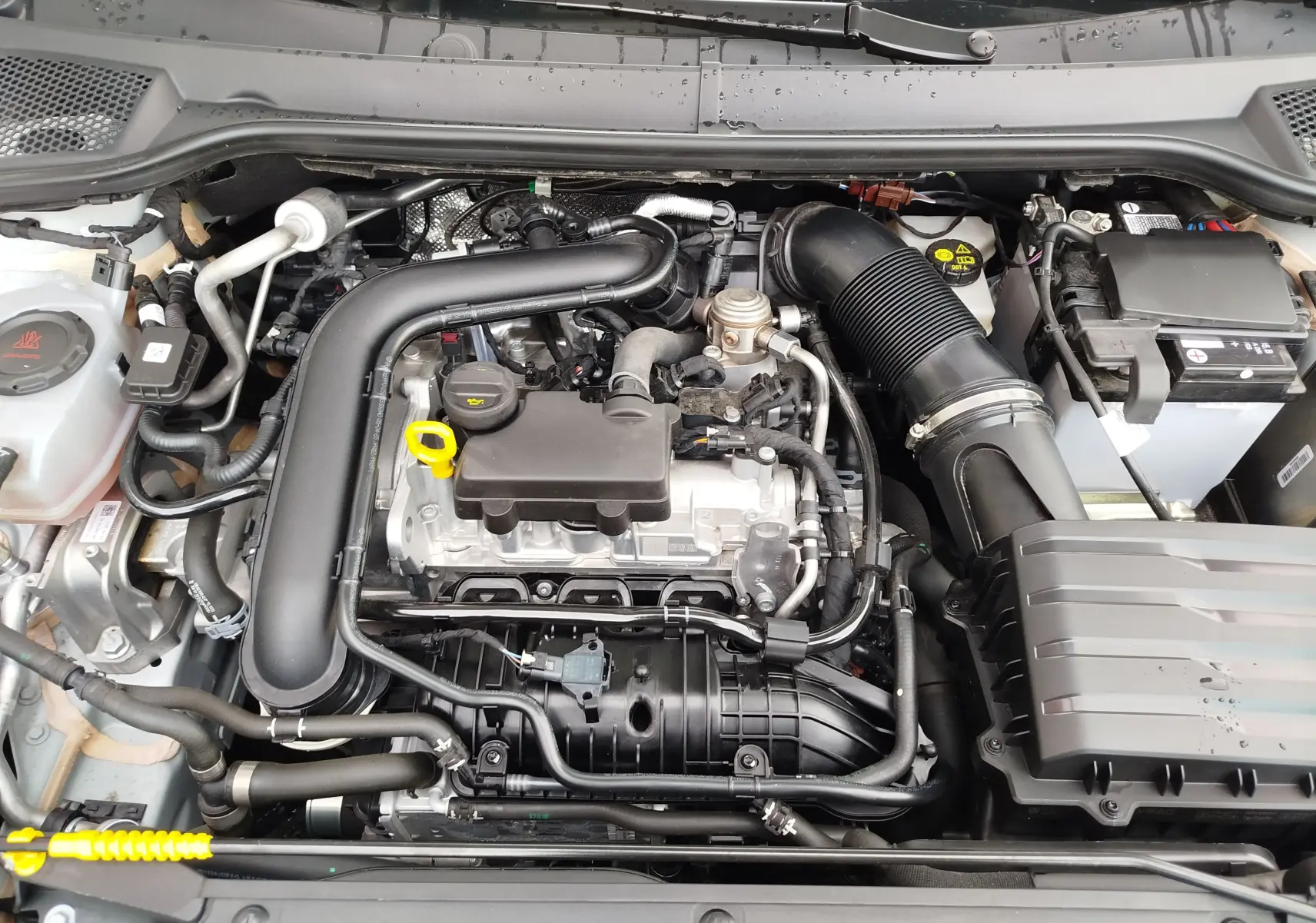 Vue rapprochée du moteur essence 1.0 TSI du SEAT Arona 2023, montrant les composants sous le capot ouvert.