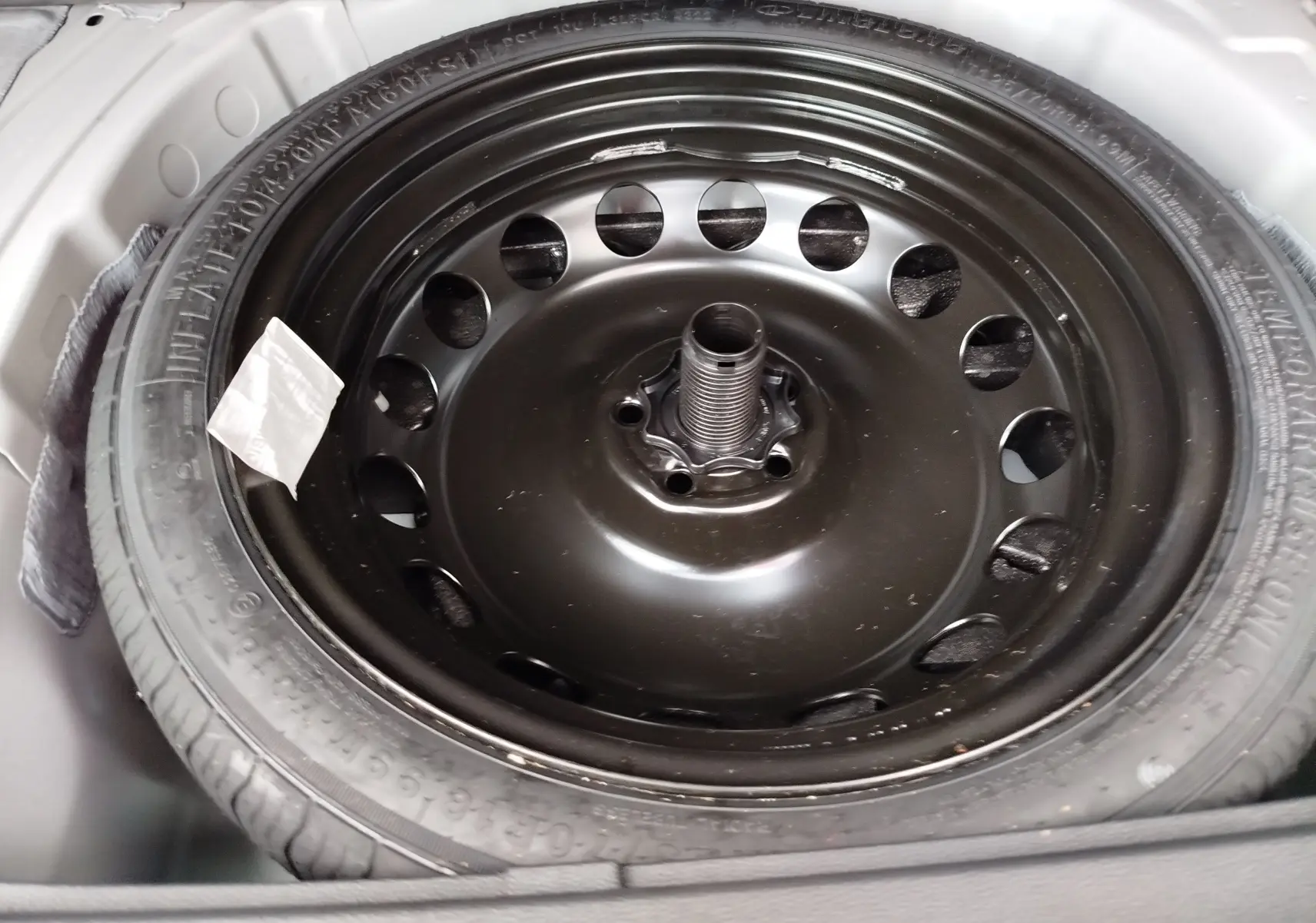 Gros plan sur la roue de secours noire du coffre d'une SEAT ARONA blanc candy 2023, version essence 1.0 TSI.