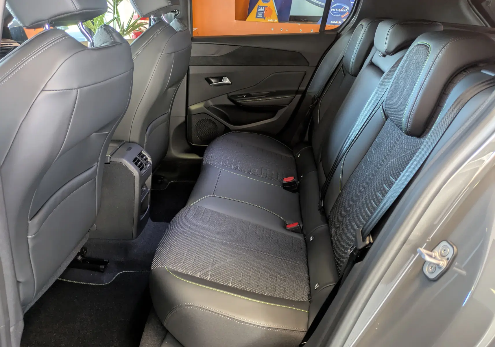Vue intérieure côté droit des sièges arrière en cuir et tissu gris avec surpiqûres vertes du Peugeot 308 Hybrid 2026.