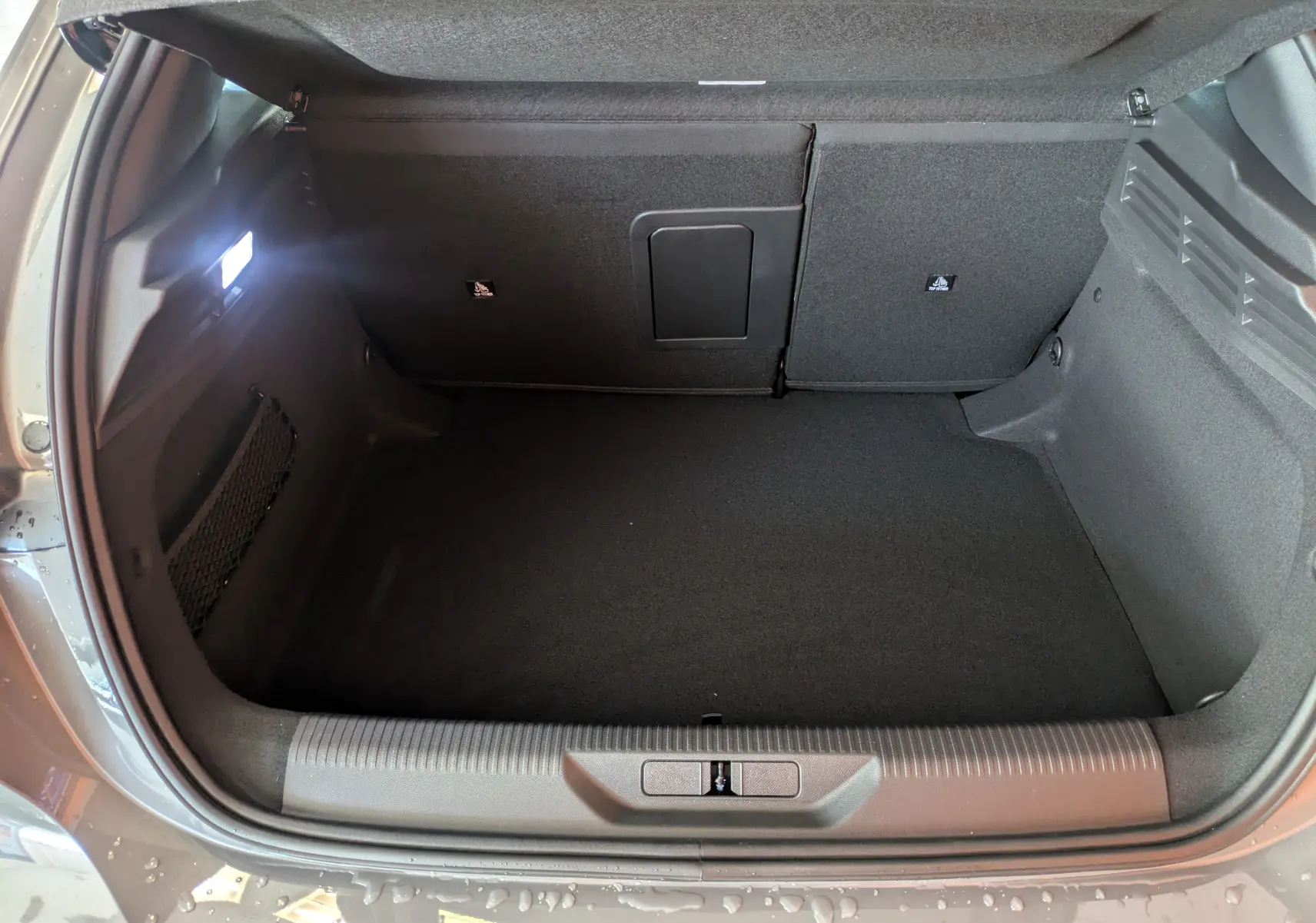 Coffre ouvert vu de dessus du Peugeot 308 gris Selenium, montrant un espace de chargement propre et bien éclairé.