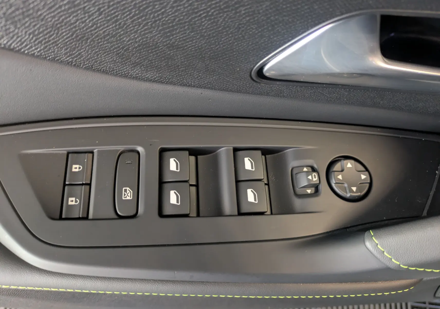 Gros plan sur les commandes de lève-vitres et rétroviseurs côté gauche intérieur d’une Peugeot 308 gris sélénium.