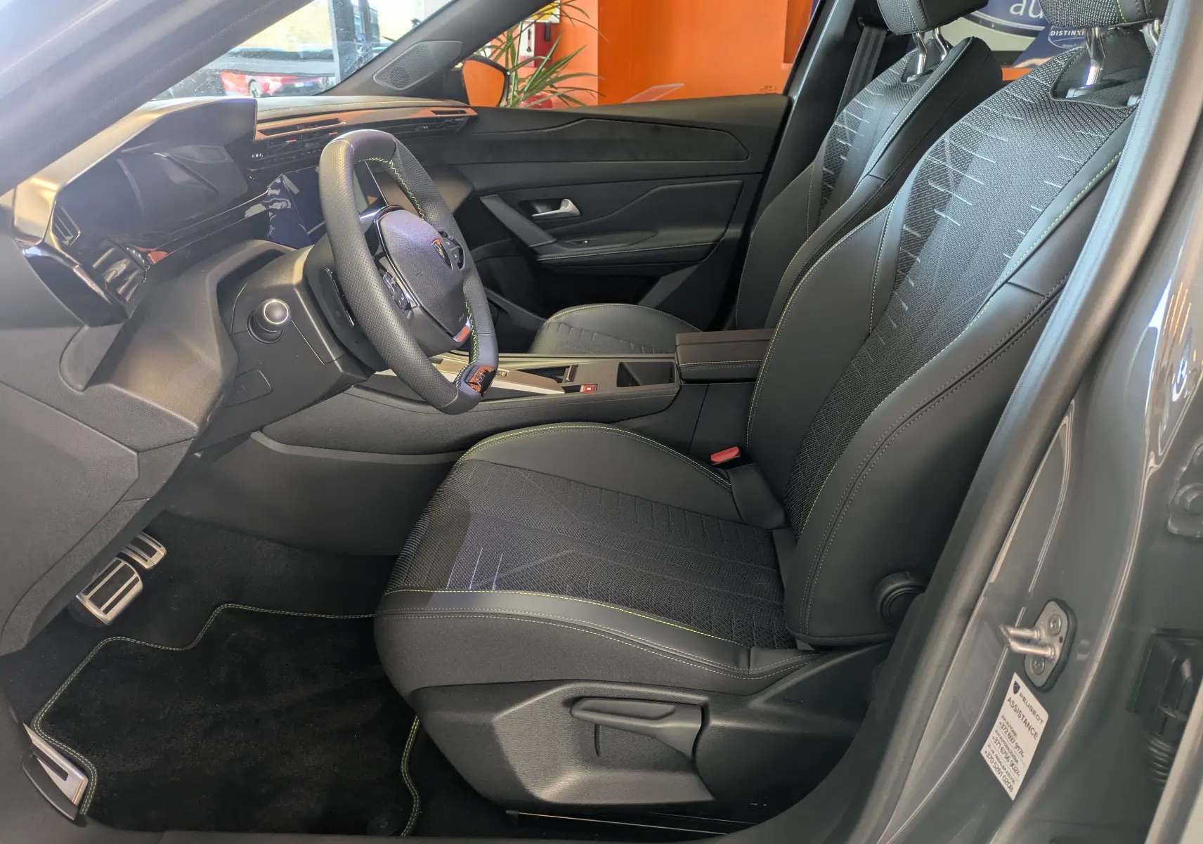 Vue intérieure côté conducteur du Peugeot 308 gris selenium, mettant en valeur les sièges sport et le volant compact.