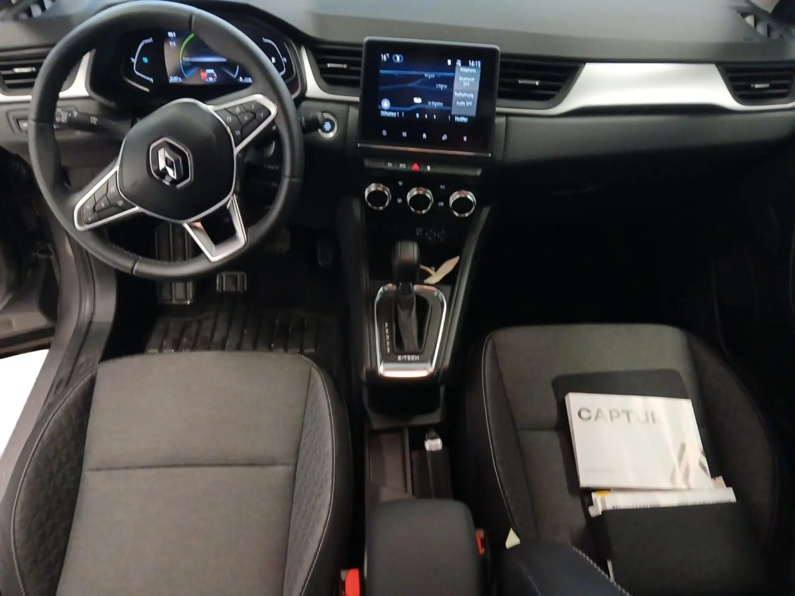 Vue intérieure du tableau de bord et console centrale du Renault Captur gris Cassiopée, avec écran tactile et volant multifonction.