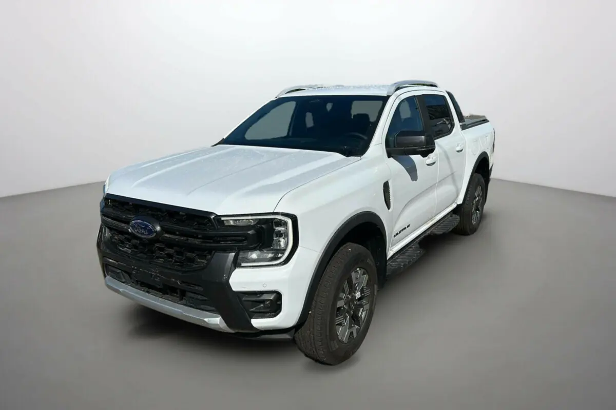 Ford Ranger blanc en 3/4 avant droit, avec calandre noire et barres de toit visibles sur fond neutre.