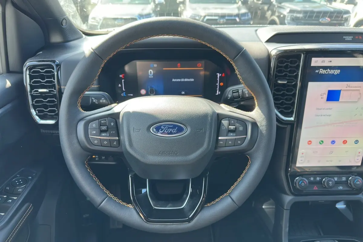Vue intérieure centrée sur le volant cuir noir avec surpiqûres marron et écran tactile du Ford Ranger blanc 2026.