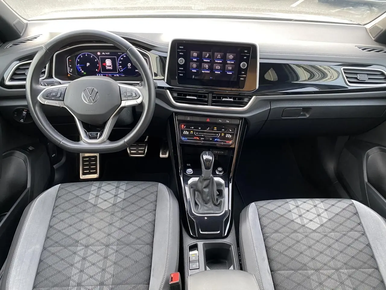 Vue intérieure du tableau de bord et console centrale du Volkswagen T-Roc 2024 avec volant multifonction et écran tactile.