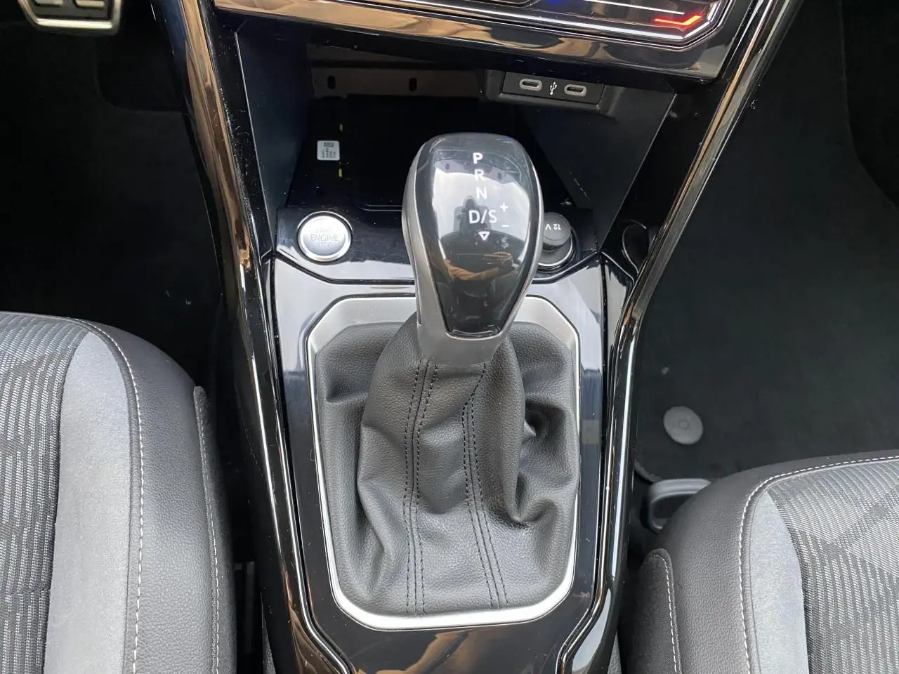 Gros plan sur la console centrale du Volkswagen T-Roc 2024 avec levier de vitesses noir et sellerie grise.