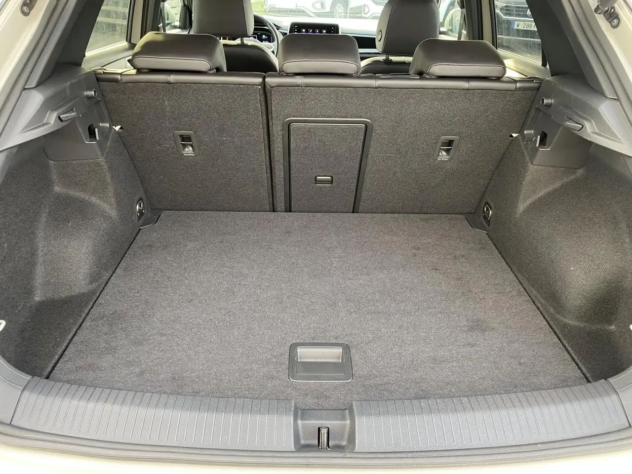 Vue du coffre ouvert du Volkswagen T-Roc gris 2024, montrant l'espace de rangement arrière et les dossiers de sièges rabattus.