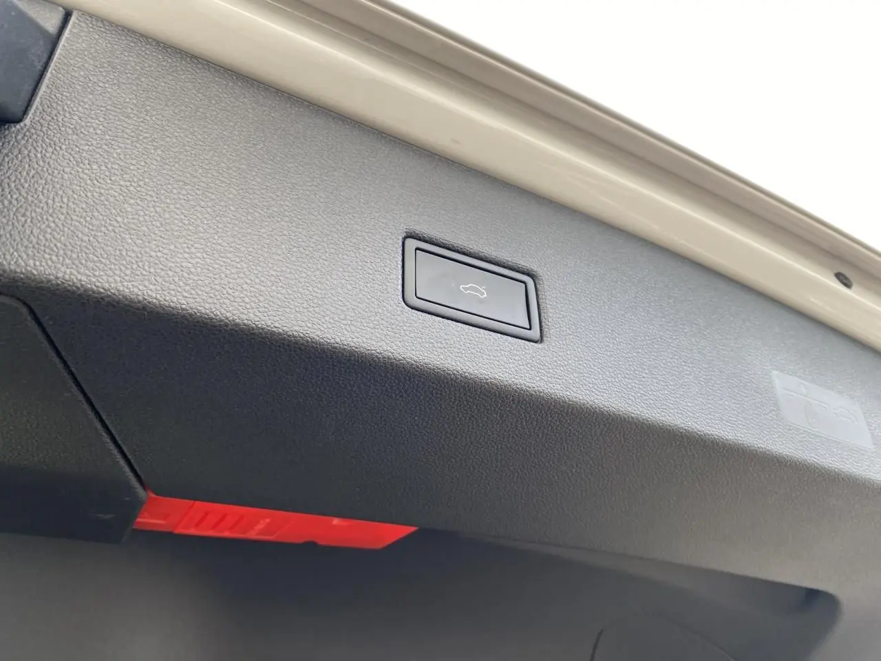 Bouton d'ouverture électrique du coffre sur la partie intérieure de la malle arrière d'une Volkswagen T-Roc grise.