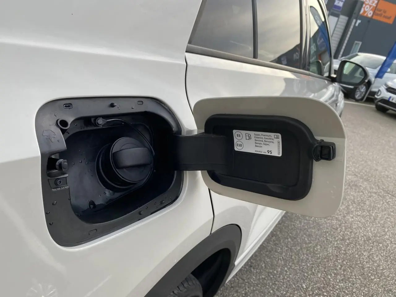 Vue rapprochée de la trappe à carburant ouverte côté gauche d’un Volkswagen T-Roc blanc.