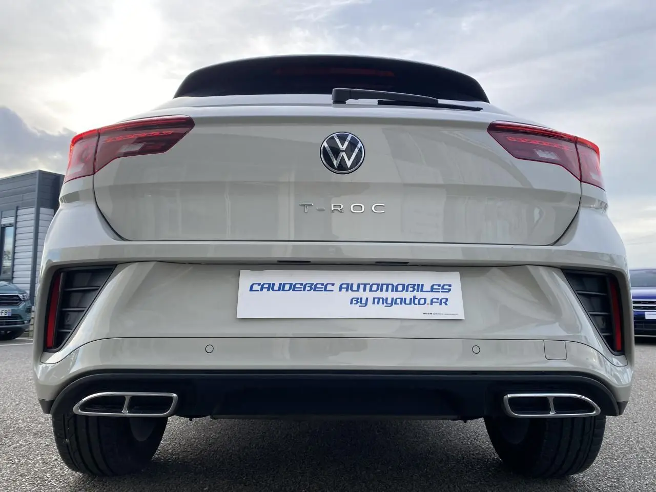 Vue arrière d'un Volkswagen T-Roc gris 2024 avec double sortie d'échappement rectangulaire et feux LED rouges.
