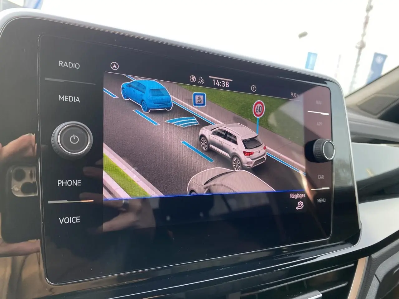 Écran tactile intérieur montrant l'assistance au maintien dans la voie avec représentation de véhicules et signalisation routière.