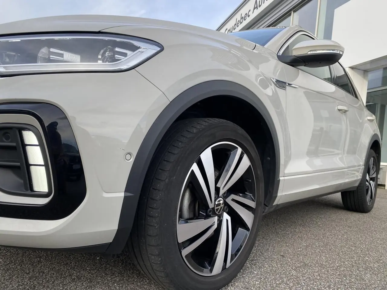 Vue 3/4 avant droit du Volkswagen T-Roc gris avec jante alliage noir et argent et détails de phares LED.