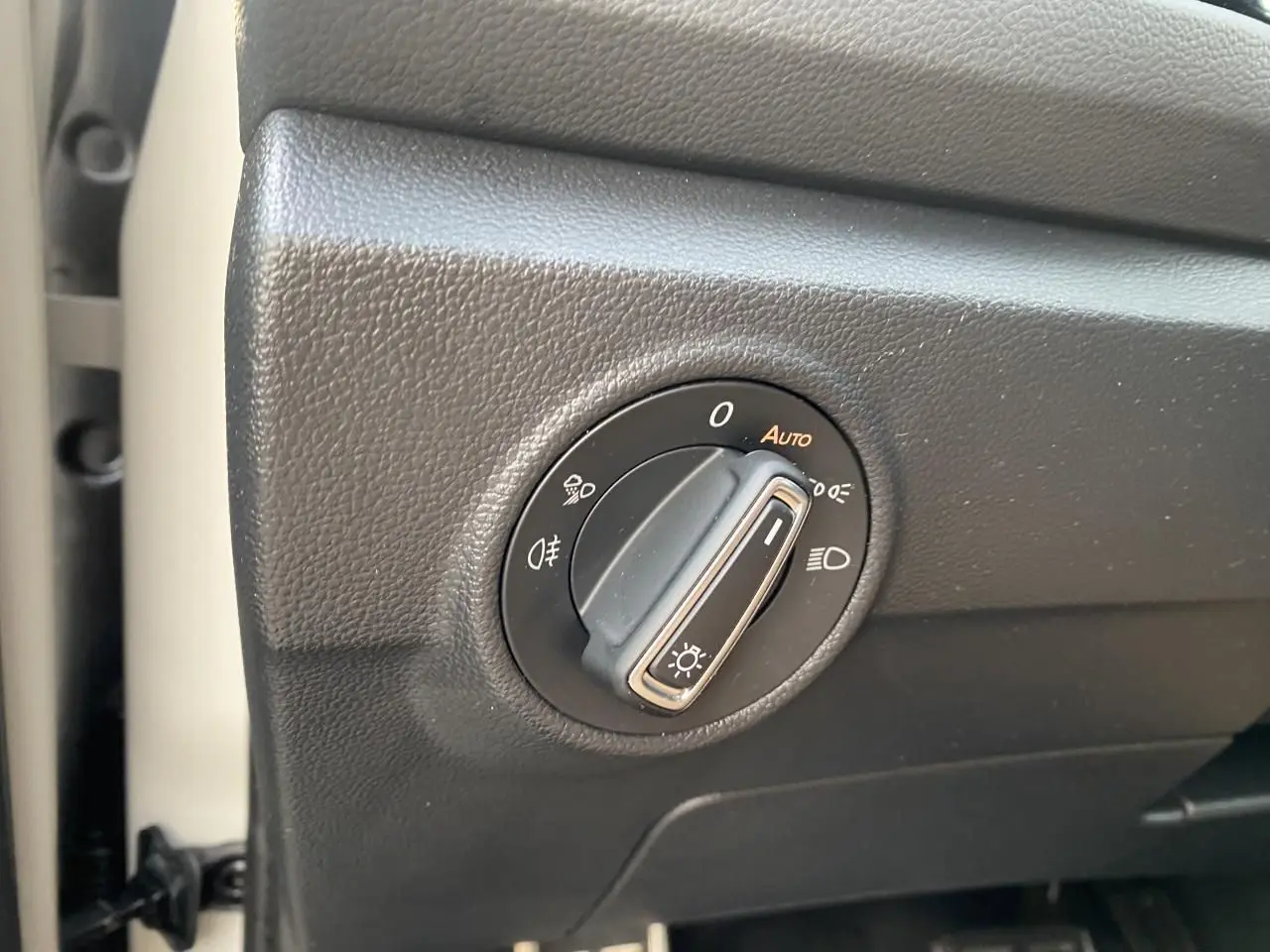 Gros plan sur le bouton de commande des phares dans l’habitacle du Volkswagen T-Roc gris 2024.