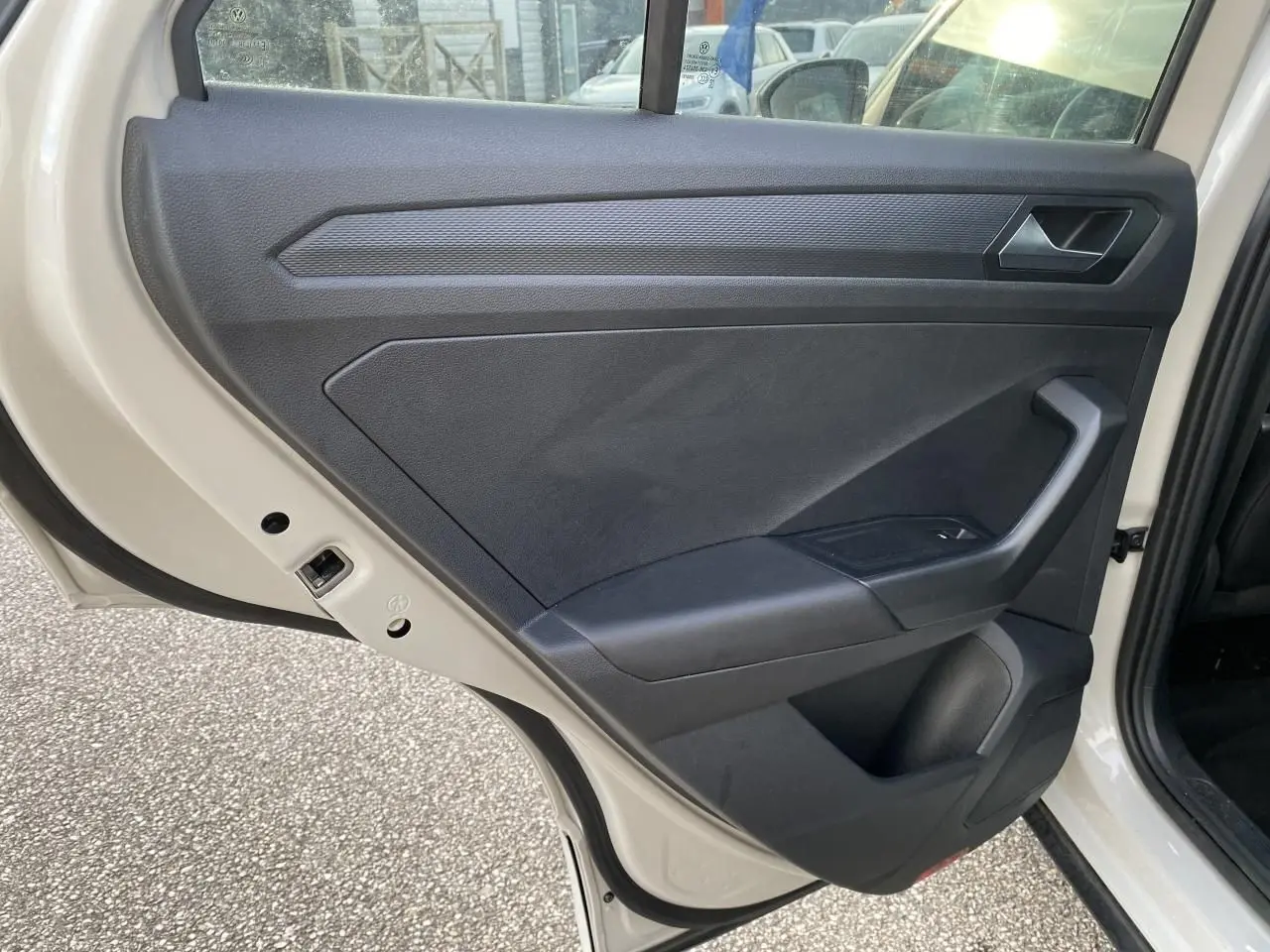 Vue intérieure de la porte arrière gauche grise d'un Volkswagen T-Roc 2024 avec garniture noire et poignée intégrée.