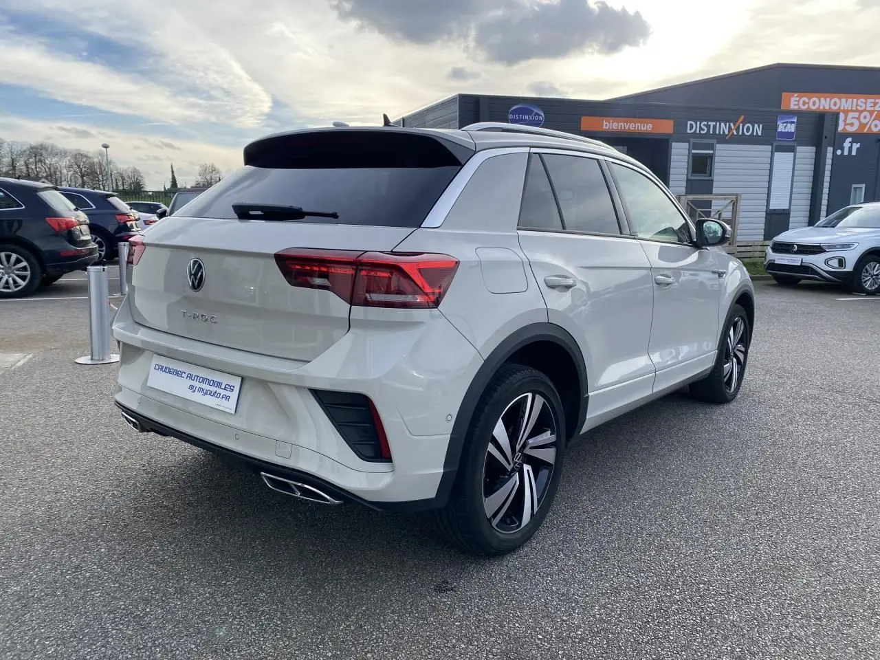 Vue 3/4 arrière droite d'un Volkswagen T-Roc gris clair avec jantes alliage noires et vitres teintées.