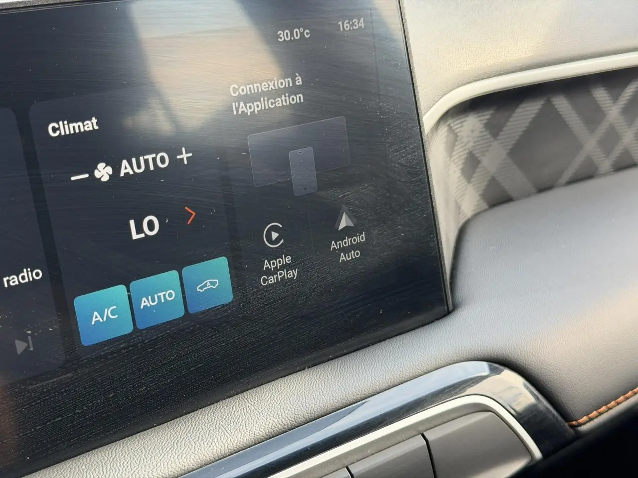 Gros plan sur l'écran tactile central et la console intérieure grise avec surpiqûres orange du MG3 1.5 Hybrid+ 2025.