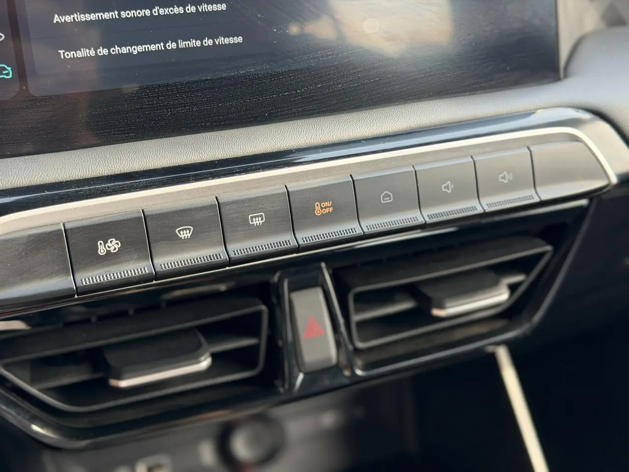 Gros plan sur la console centrale du MG3 1.5 Hybrid+ 195 Comfort, montrant les boutons de climatisation et les aérateurs noirs.