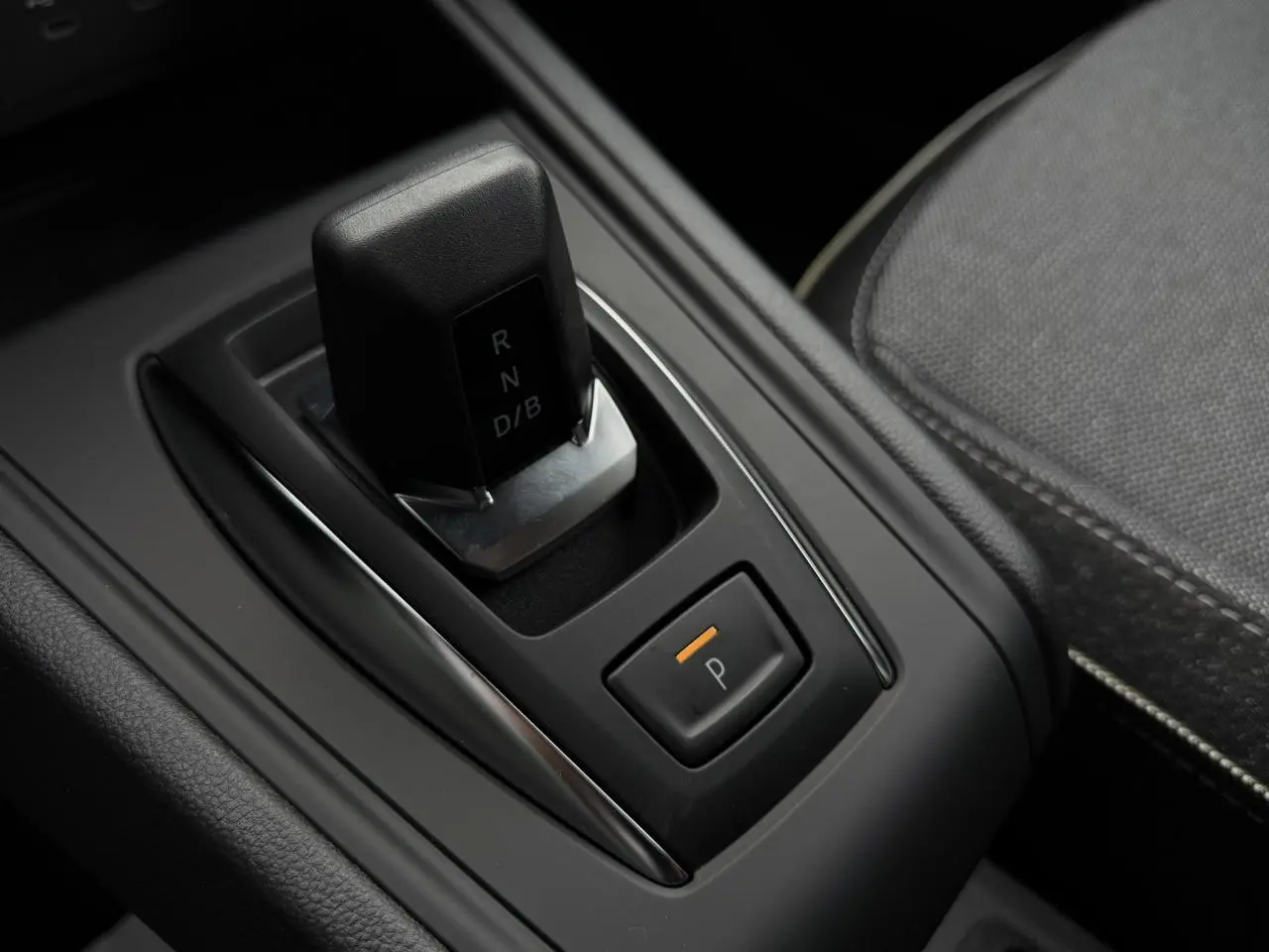 Gros plan sur la commande de boîte automatique noire et bouton de parking orange dans l’habitacle du Renault Captur 2026.