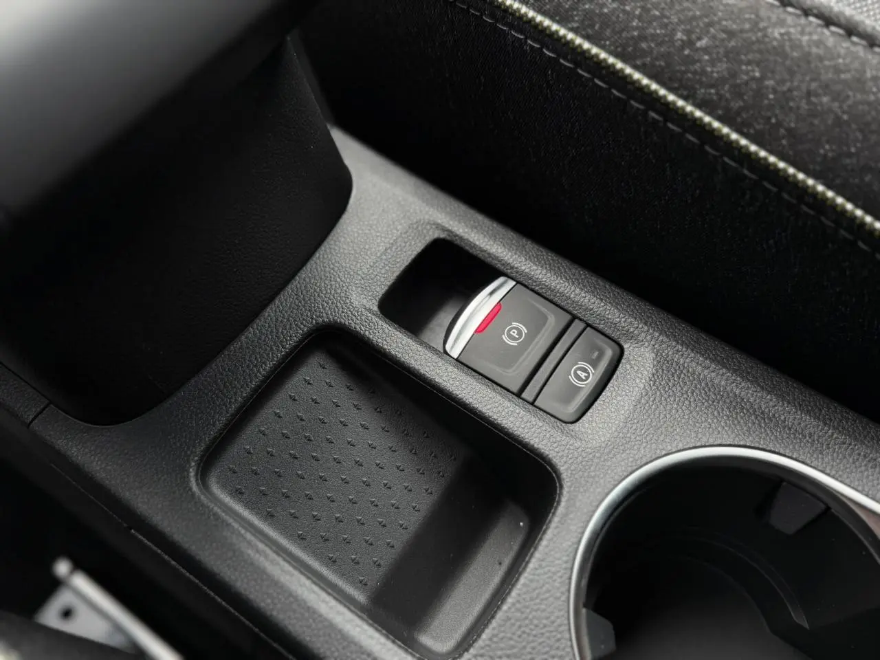 Gros plan sur la console centrale noire du Renault Captur 2026, avec frein à main électrique et rangement.