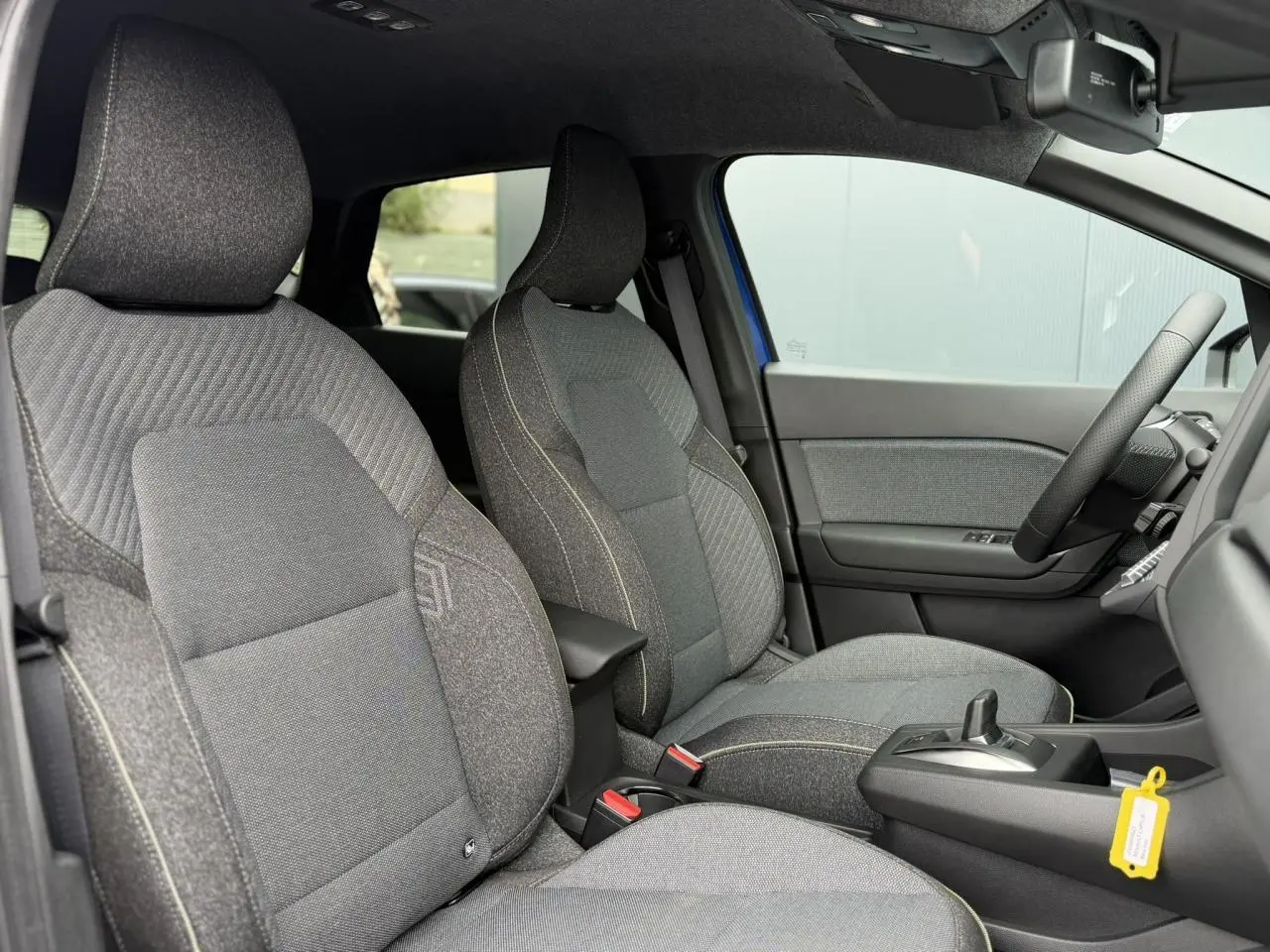 Vue intérieure côté droit du Renault Captur 2026 bleu Iron, sièges tissu gris avec coutures contrastées.