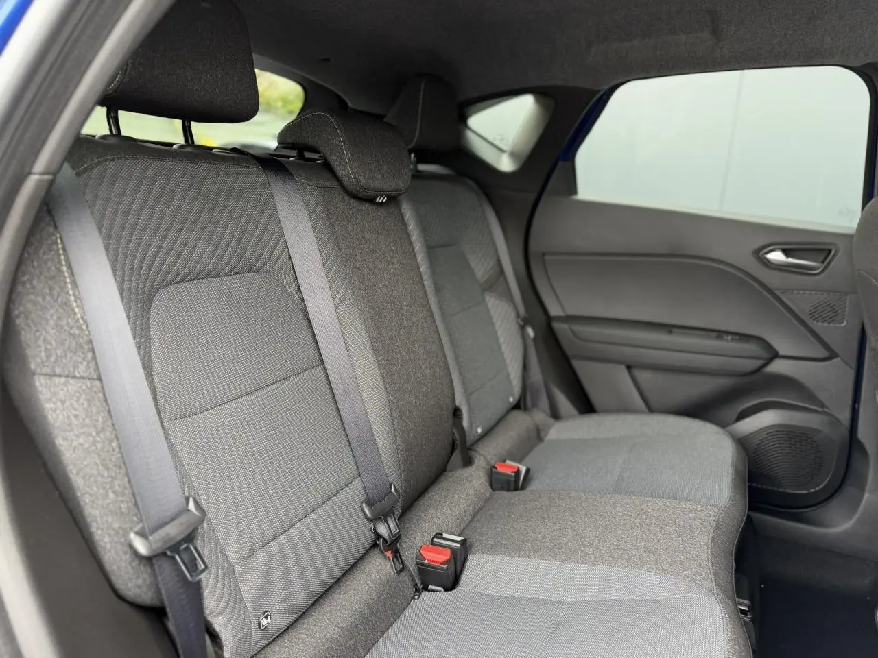 Vue intérieure arrière côté droit des sièges gris foncé du Renault Captur 2026 avec ceinture et porte de teinte sombre.