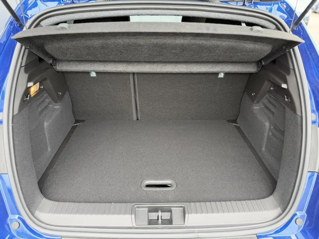 Coffre ouvert vu de l'arrière du Renault Captur bleu Iron, montrant un espace de chargement propre et spacieux.