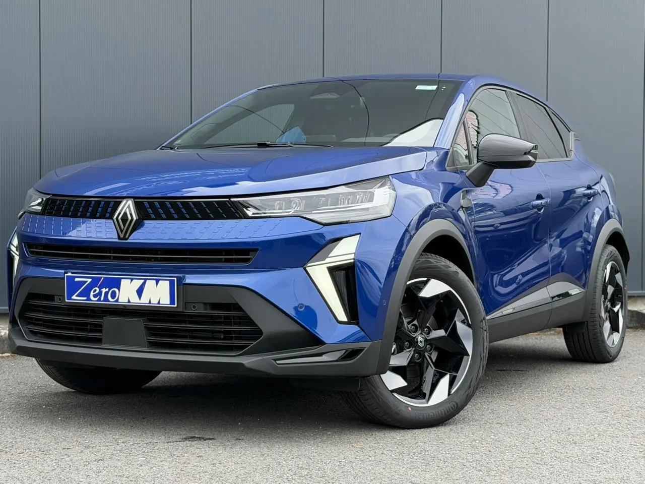 Renault Captur bleu Iron en 3/4 avant droit, avec jantes 18" Black Hole et calandre moderne noire brillante.