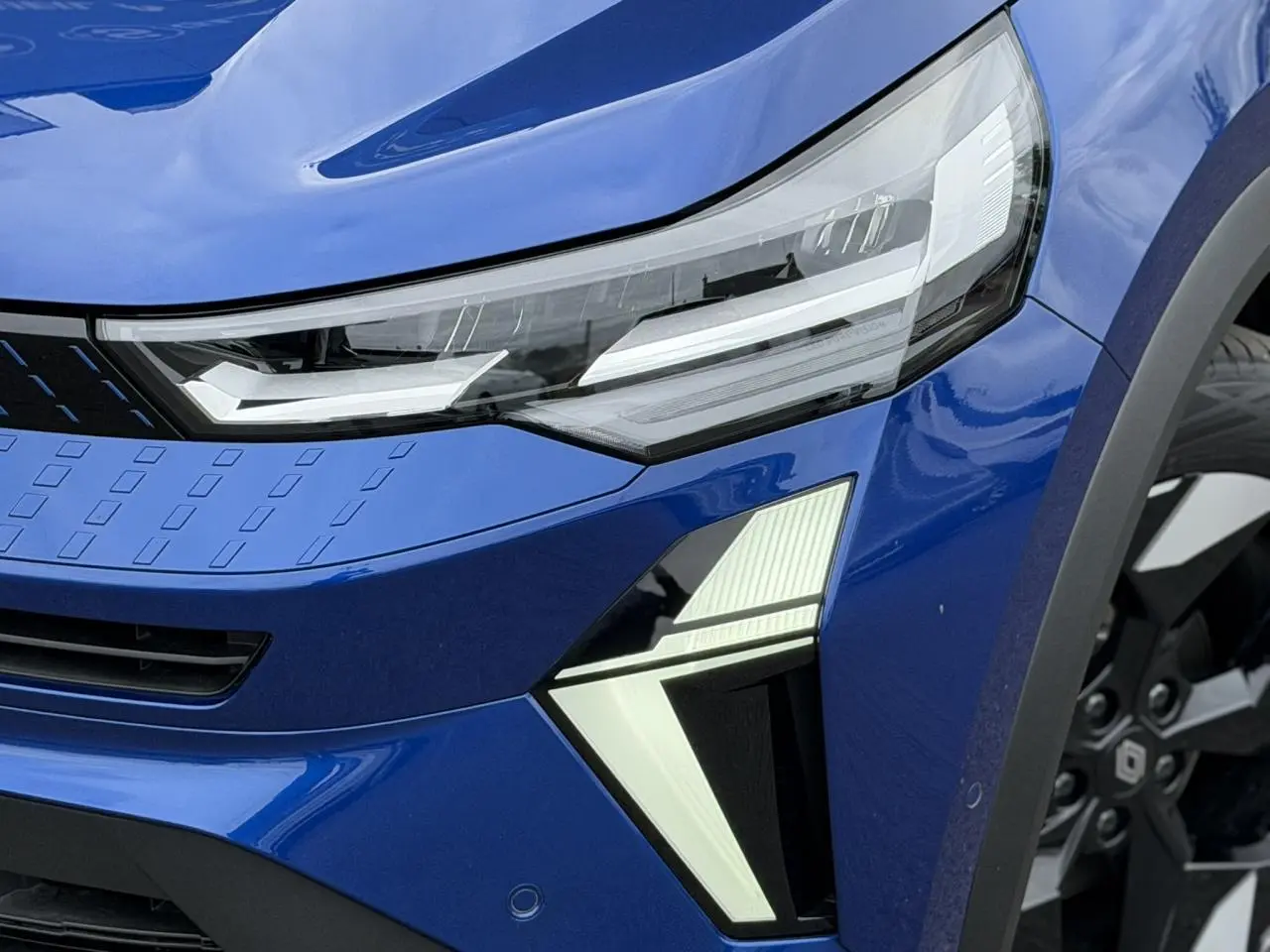 Gros plan sur l'avant droit du Renault Captur Bleu Iron, mettant en valeur le phare LED et la jante aluminium 18 pouces.