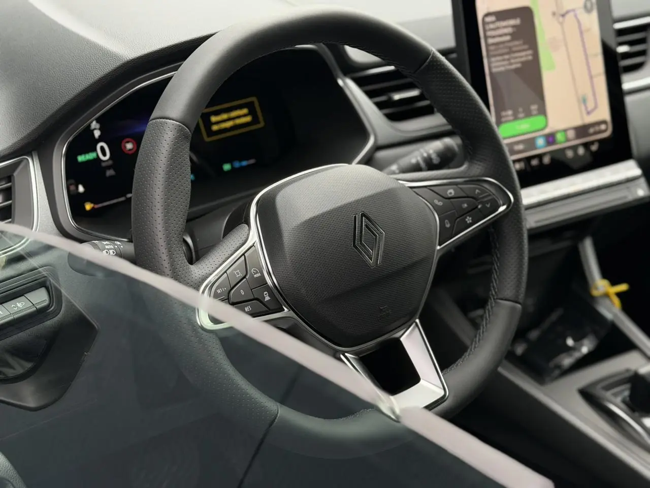 Vue rapprochée du volant noir et du tableau de bord numérique du Renault Captur 2026, avec écran tactile central.