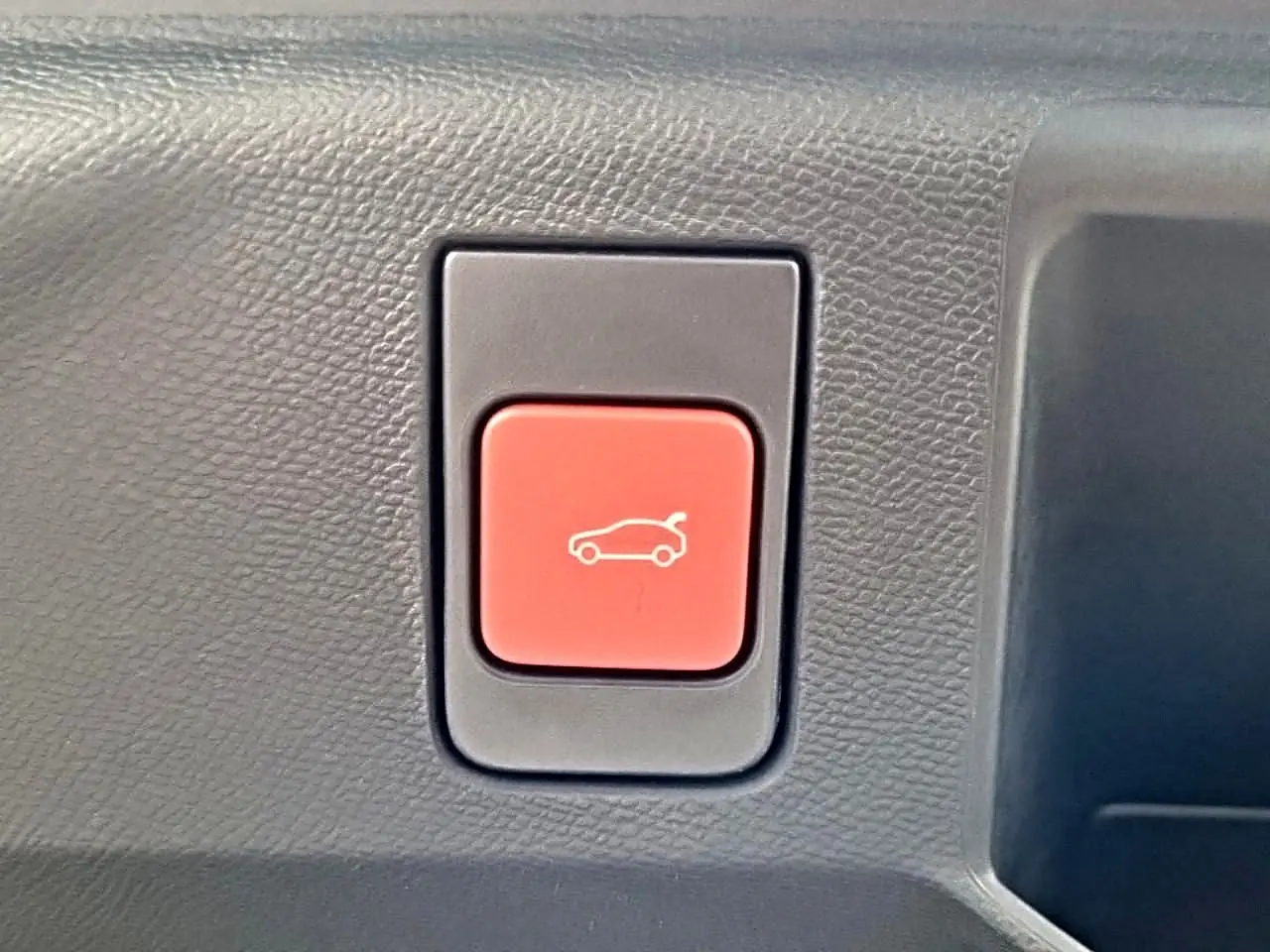 Bouton rouge d'ouverture électrique du hayon sur panneau intérieur noir du Peugeot 5008 Hybrid 145 GT e-dcs6.