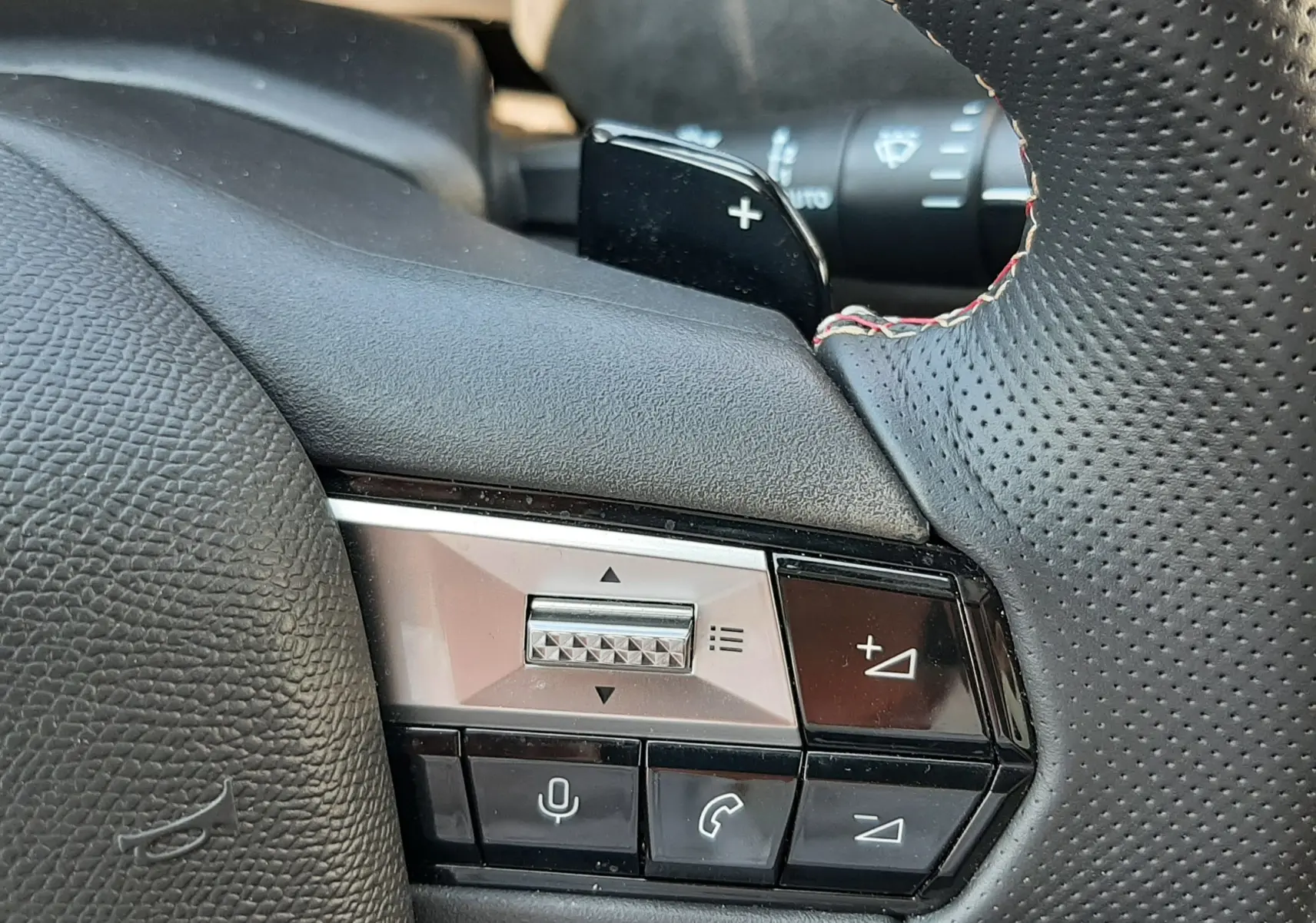 Gros plan sur la commande droite du volant en cuir perforé noir avec surpiqûres rouges du DS4 Cristal Pearl 2024.