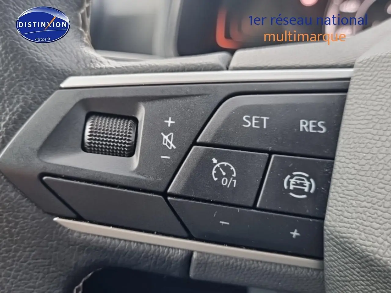 Gros plan sur les commandes du volant multifonction d'une SEAT Ibiza rouge désir, version 2025.