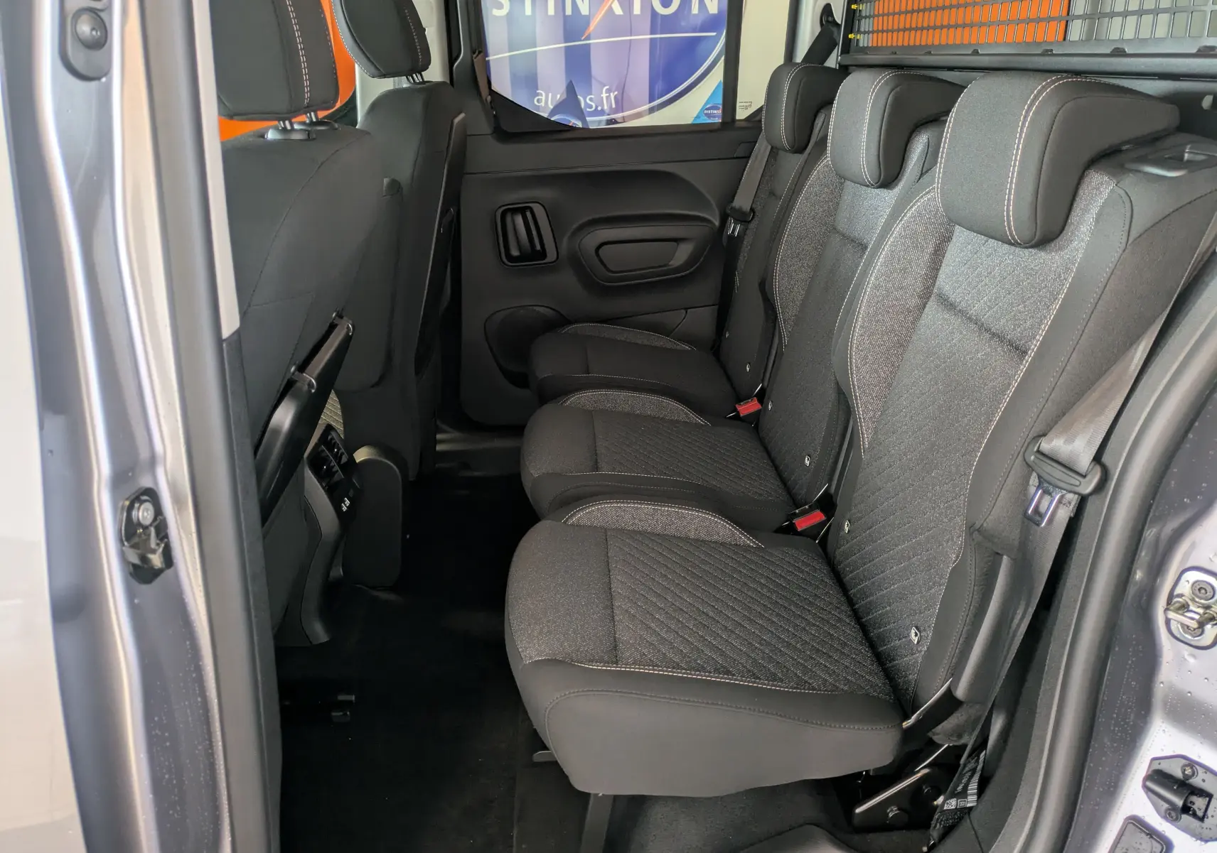 Vue intérieure côté droit des sièges arrière gris foncé du Peugeot Rifter 2025, avec porte ouverte et sellerie tissu.