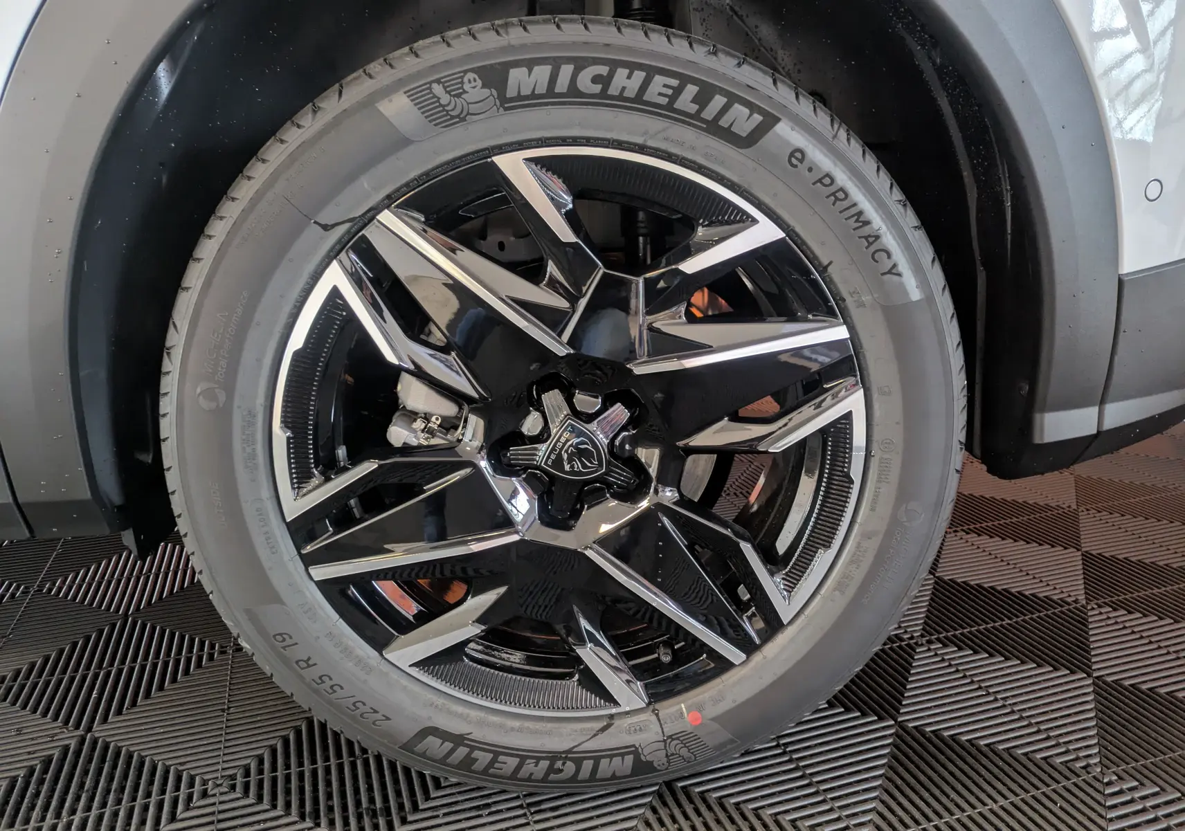 Gros plan sur la roue avant droite du Peugeot 3008 blanc Okenite, avec jante alliage noire et détails chromés.