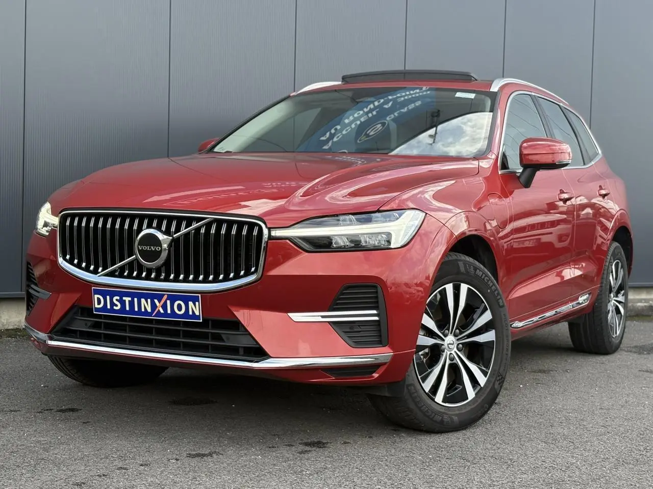 Vue 3/4 avant droit du Volvo XC60 T6 AWD PHEV rouge Fusion avec calandre chromée et jantes alliage 18 pouces.
