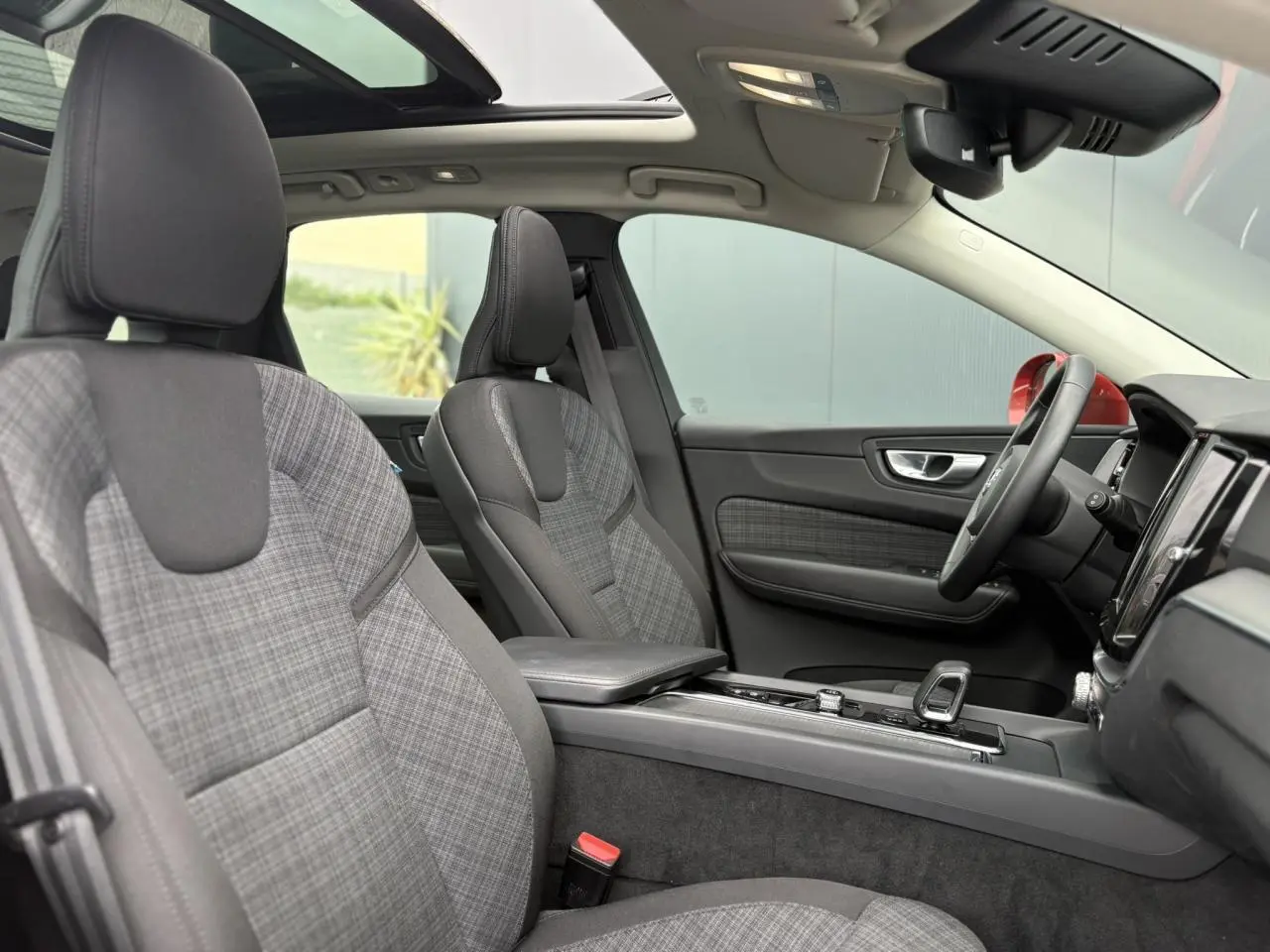 Vue intérieure côté droit du Volvo XC60 2024, sièges tissu gris à motif carreaux et toit ouvrant panoramique.