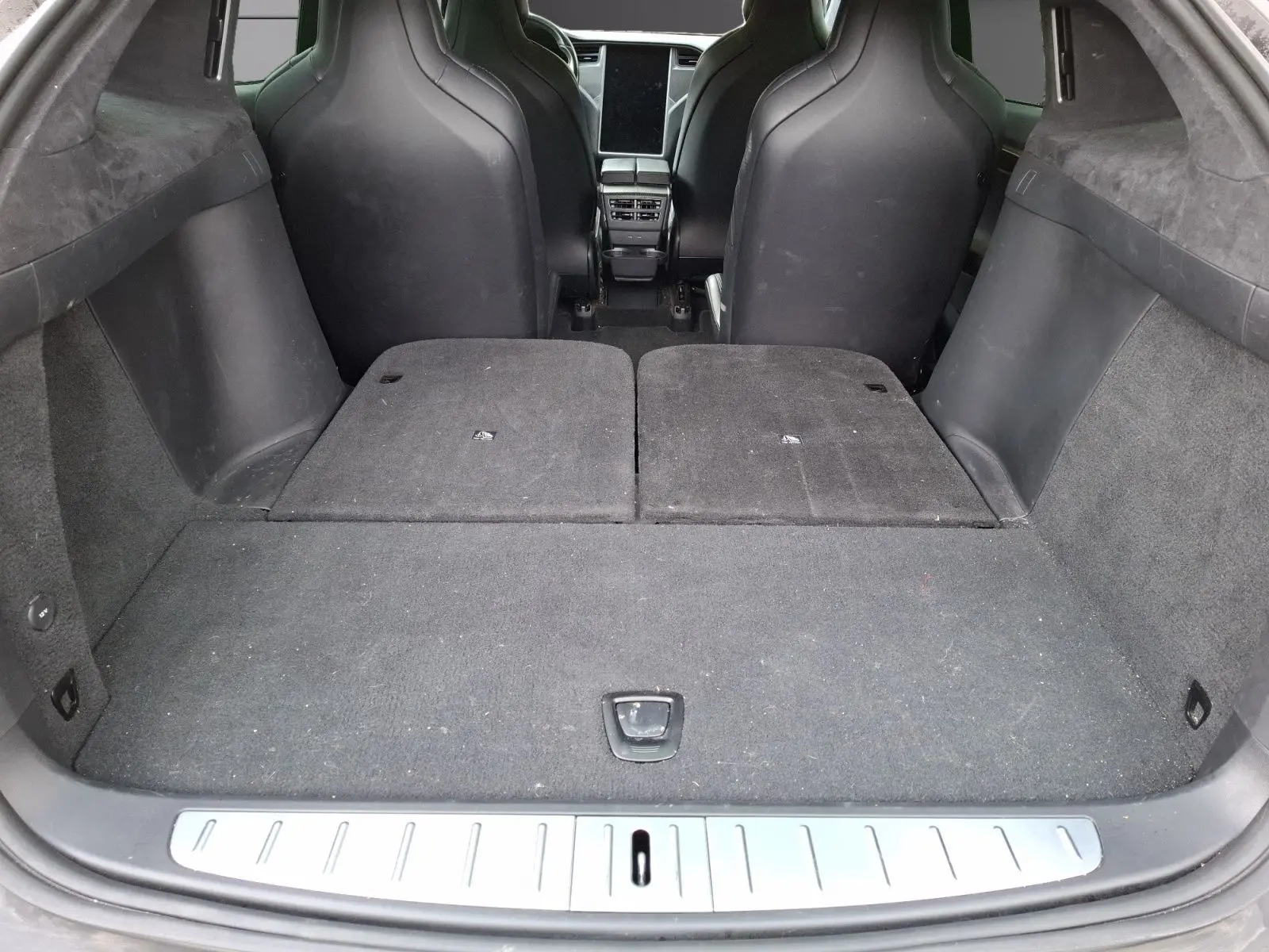 Vue depuis le coffre du Tesla Model X 100D gris foncé, sièges arrière rabattus et espace de chargement plat.