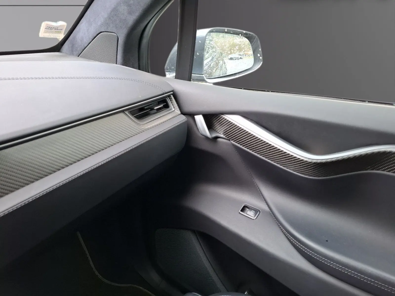 Intérieur côté passager du Tesla Model X 100D 2018, montrant la porte avec insert carbone et tableau de bord gris foncé.