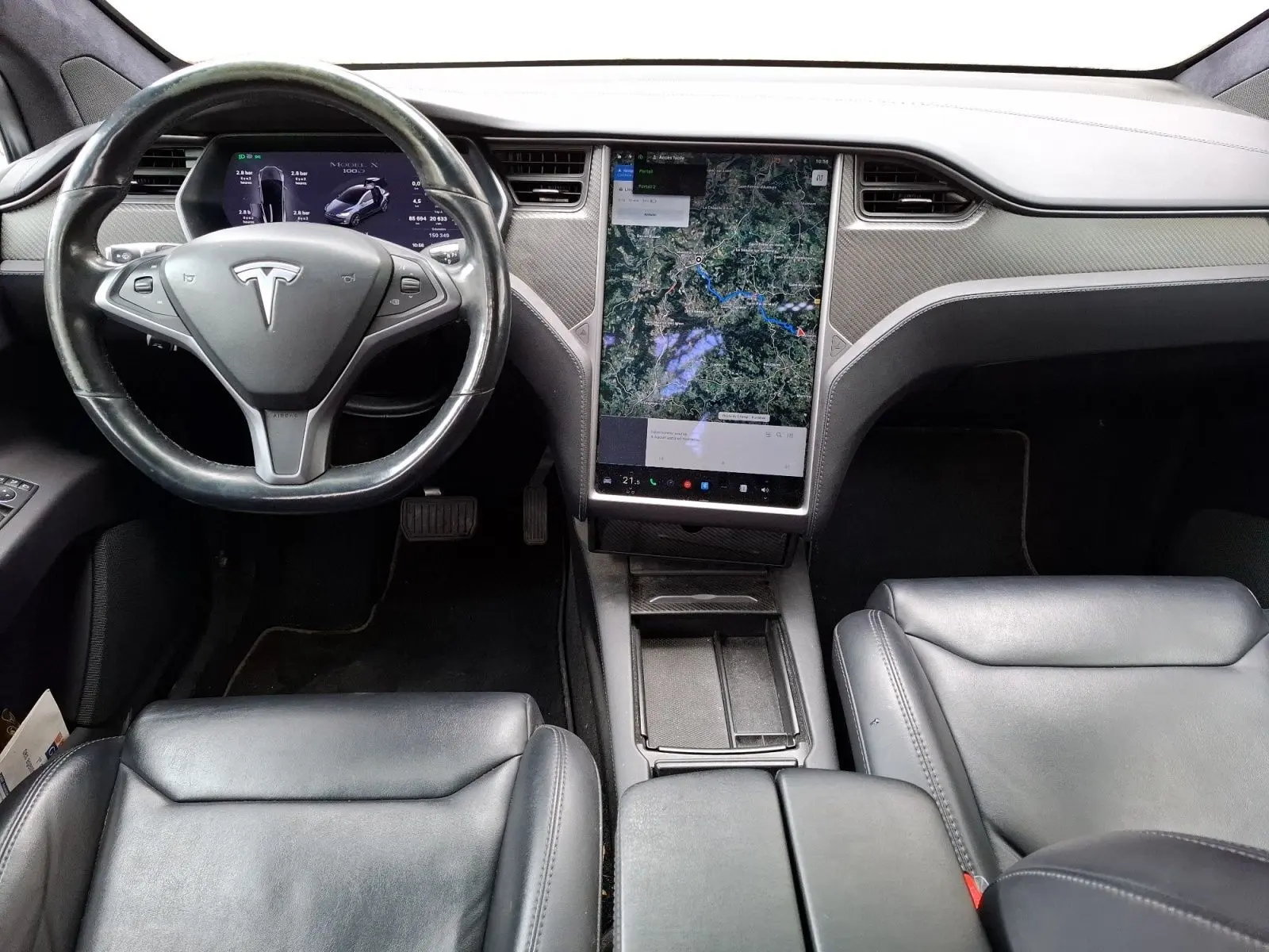 Vue intérieure frontale du tableau de bord de la Tesla Model X 100D 2018 avec écran tactile vertical et volant noir.