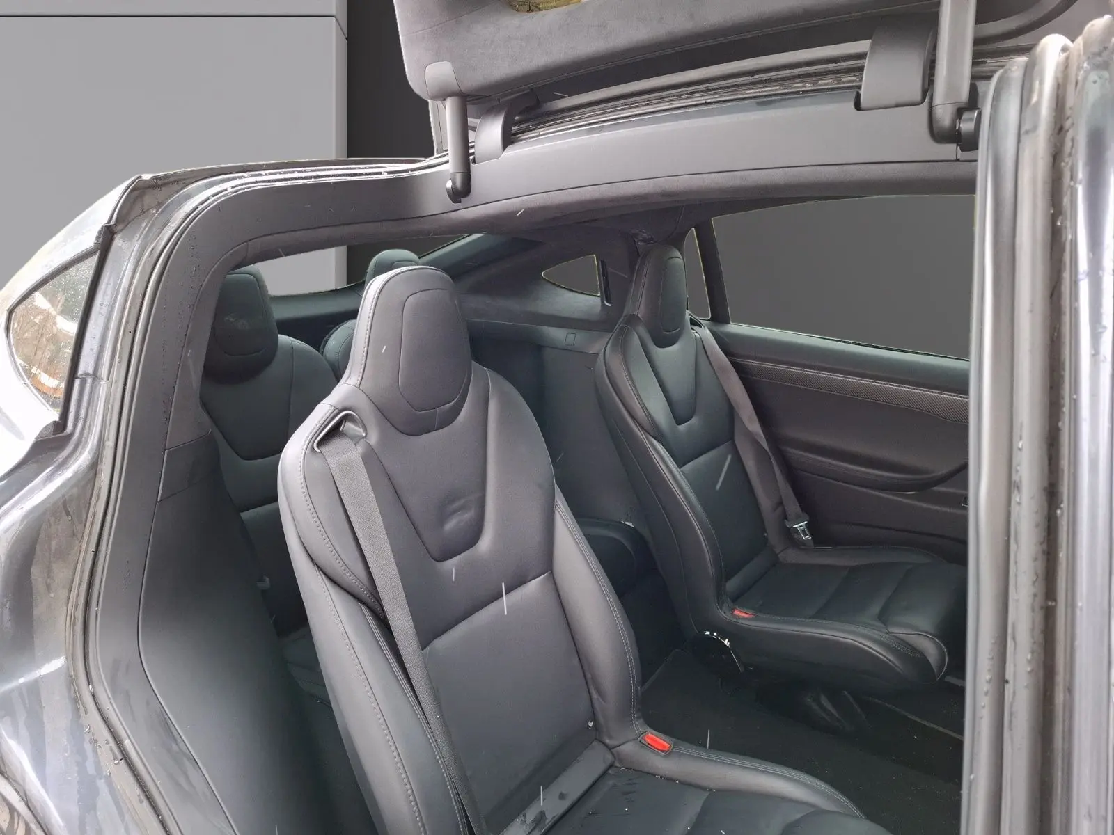 Vue intérieure côté droit du Tesla Model X 100D gris foncé, montrant les sièges en cuir noir et la porte ouverte avec porte-à-faux caractéristique.