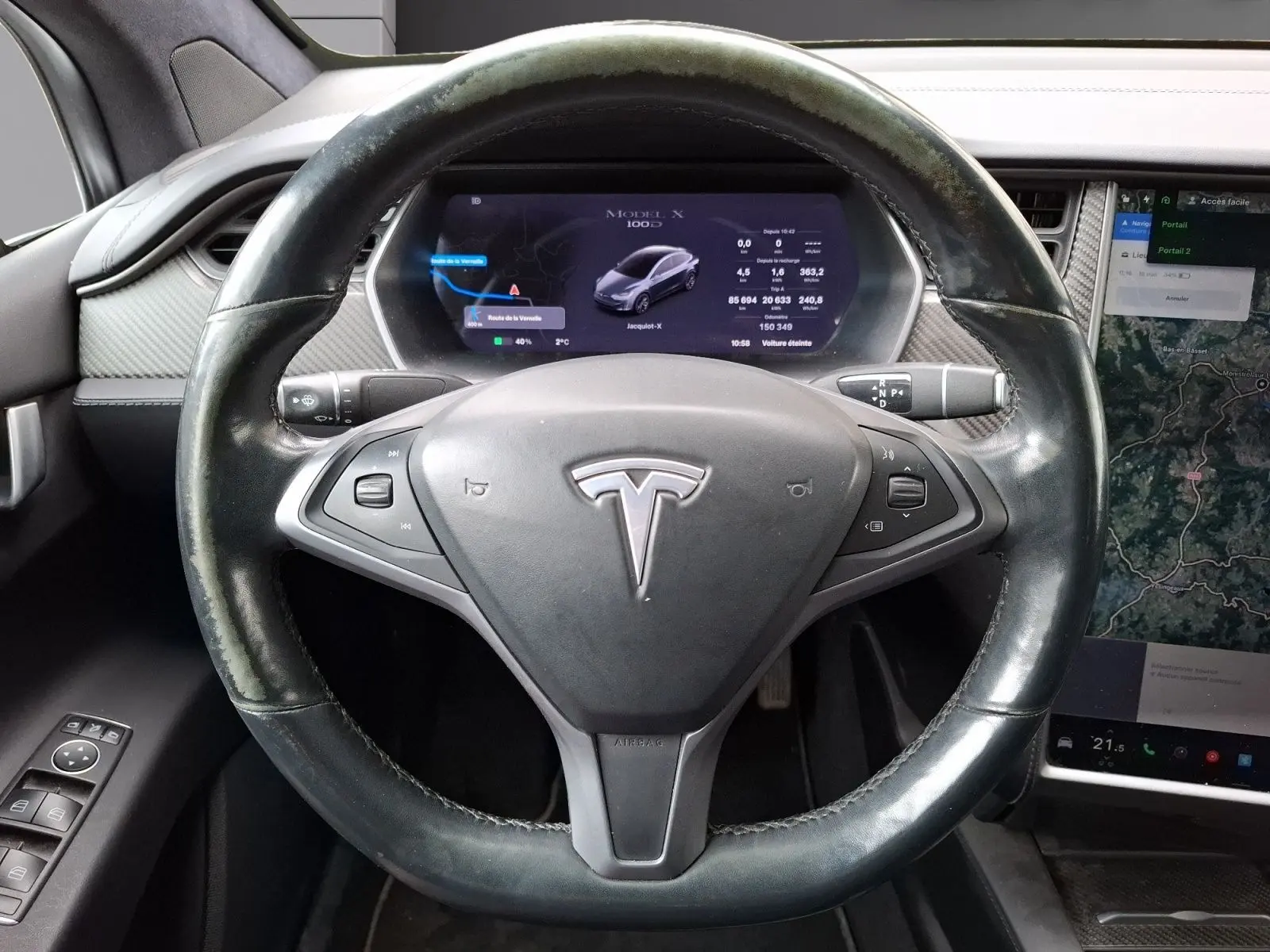 Vue rapprochée du volant noir de la Tesla Model X 100D avec écran numérique et console tactile visible.